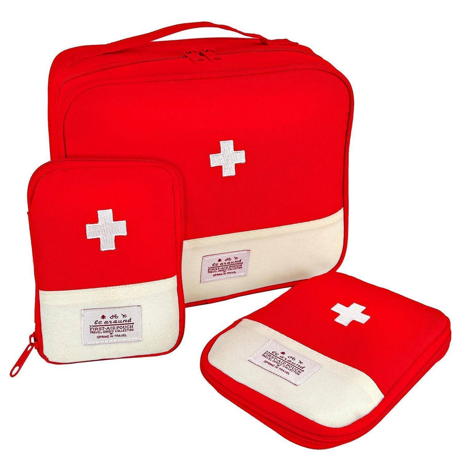 Rotes Erste-Hilfe-Set: große Tasche mit Reißverschluss, kleinere Tasche und flache Schachtel, jeweils mit weißem Kreuzzeichen und cremefarbenem Bodenpanel.