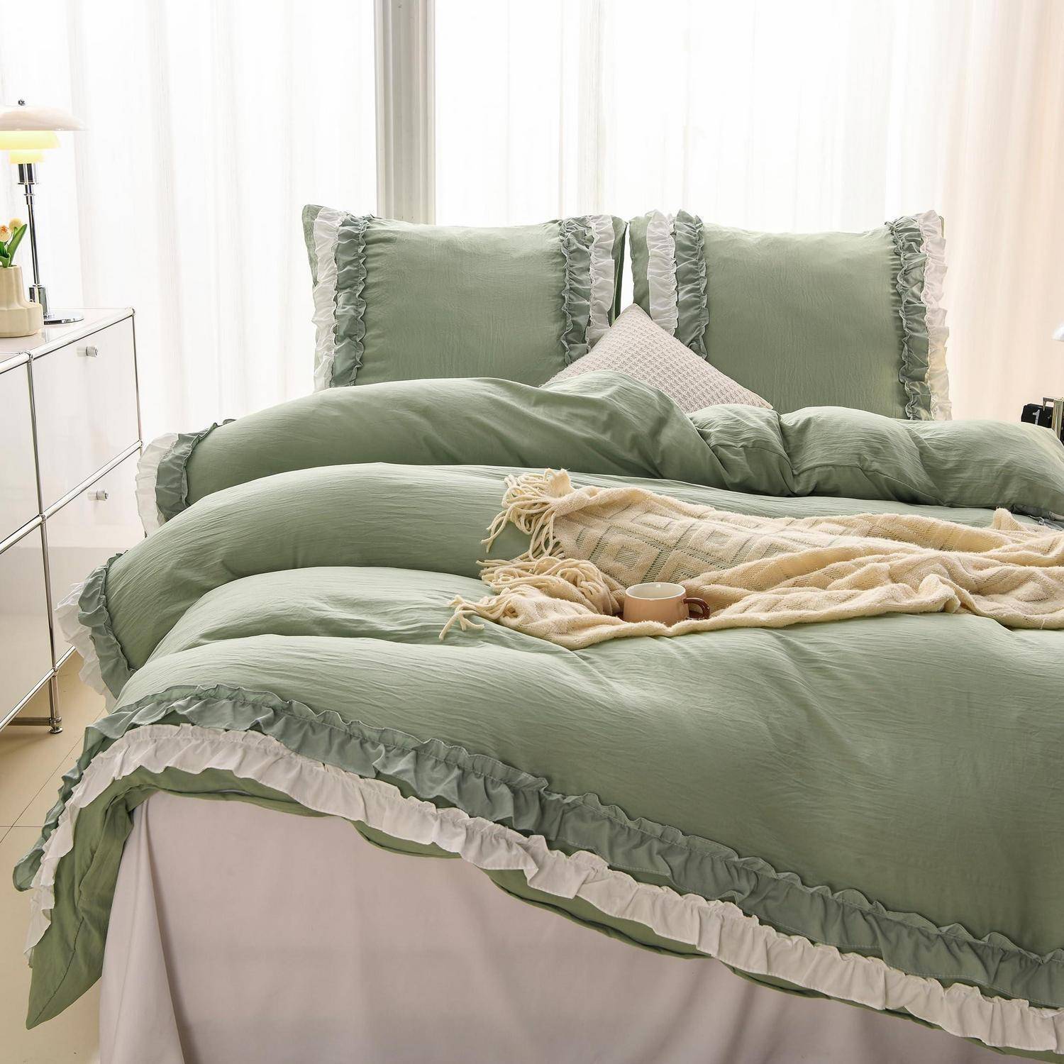 Ein ordentlich gemachtes Bett mit Salbeigrünem Rüschenbettwäsche und Kissen, akzentuiert durch eine cremefarbene Wurfdecke und ein Tablett in einem hellen Schlafzimmer.