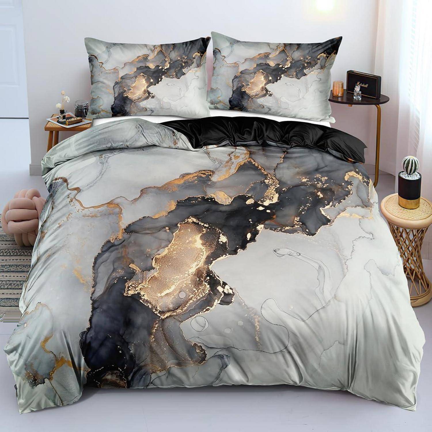 Bett mit Bettwäsche im abstrakten Marmormuster in Grau, Schwarz und Gold, bestehend aus zwei passenden Kissen und einer Bettdecke.