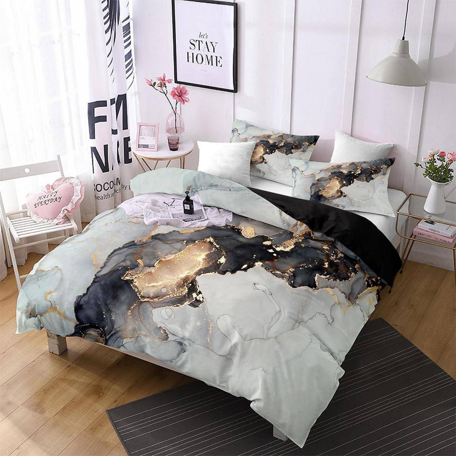 Ein Bett mit abstrakt gemusterter Marmor-Bettwäsche in Grau, Schwarz und Gold, gezeigt in einem hellen, modernen Schlafzimmer.