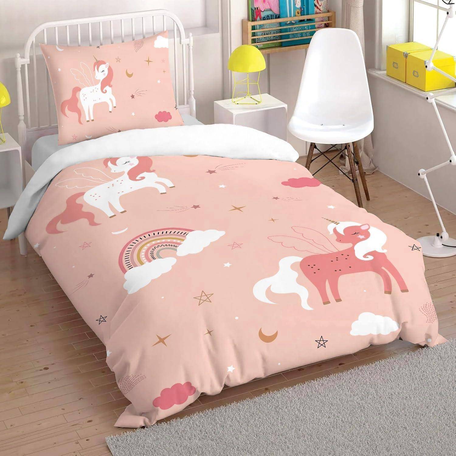 Rosa Einhornbettwäsche auf einem Bett in einem Kinderzimmer, mit passendem Kissenbezug und Bettdeckenbezug mit Sternen, Wolken und Regenbögen.