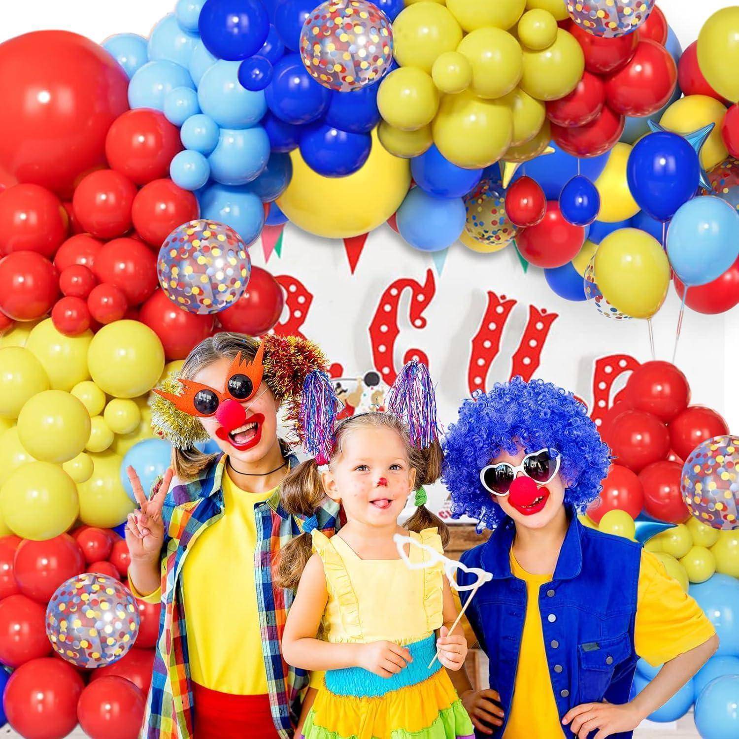 Drei Kinder in Clownkostümen posieren vor einer bunten Partydekoration mit Luftballons und dem Wort „CIR".