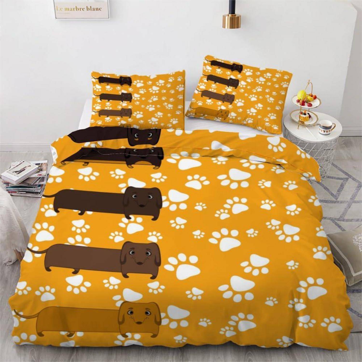 Orangefarbenes Bettwäscheset mit Cartoon-Dackelund weißen Pfötchendrucken, inklusive passender Kissenbezüge, auf einem ordentlich gemachten Bett.