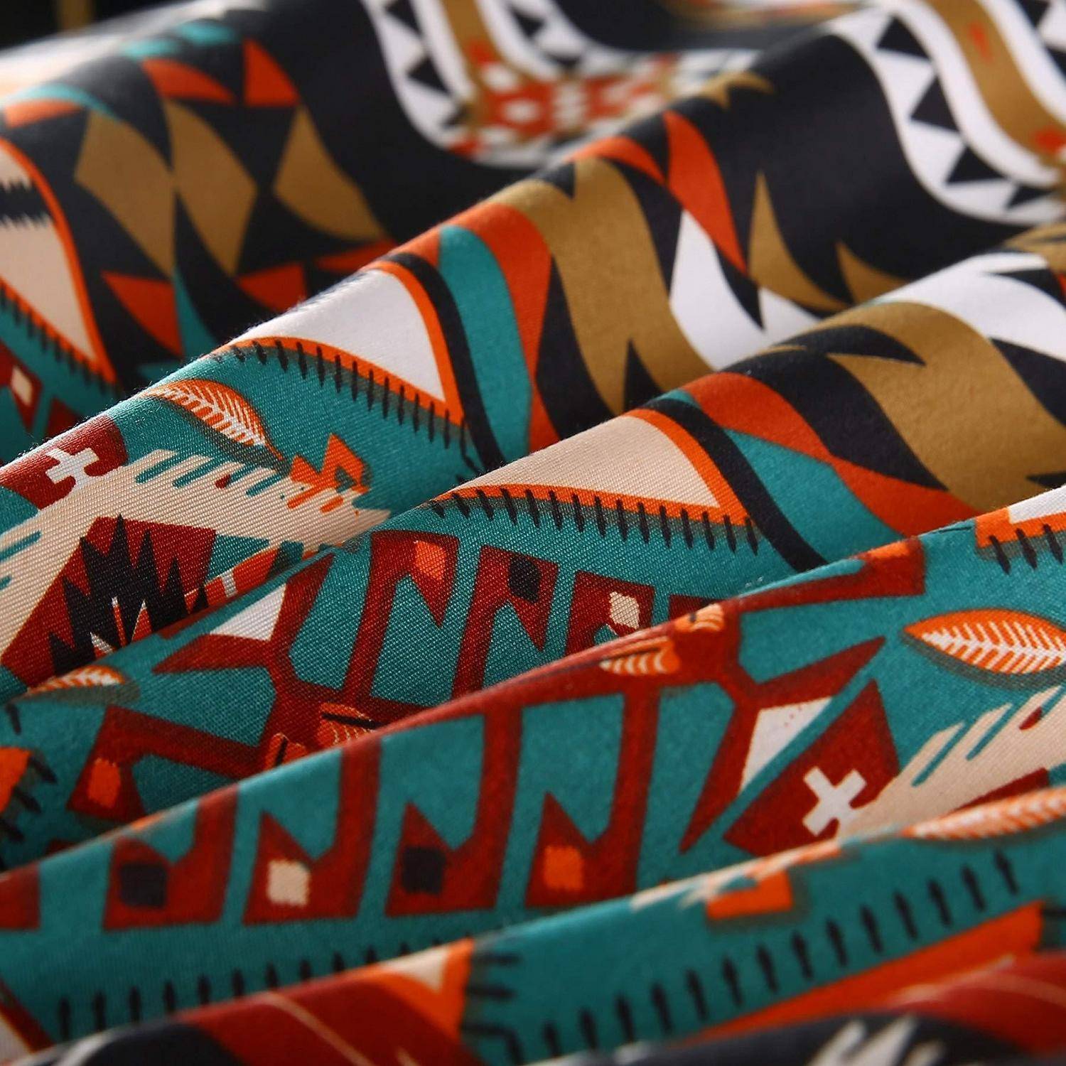 Nahaufnahme von gefaltetem Musterstoff mit kühnen geometrischen Formen in Blaugrün, Orange, Rot, Schwarz und Creme.