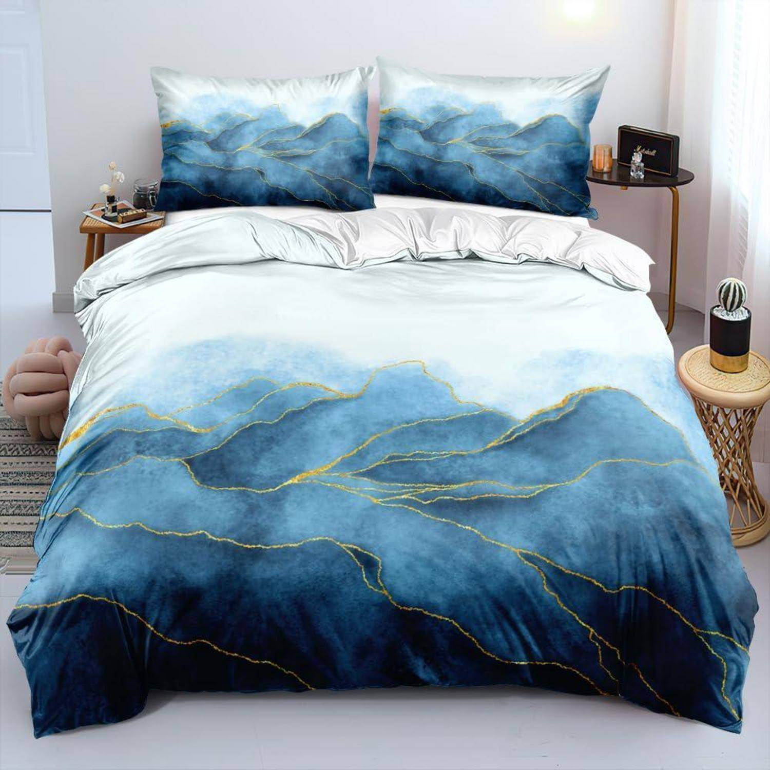 Bett mit blauer und goldener abstrakter Gebirgsmuster-Bettwäsche, einschließlich passendem Bettdeckenüberzug und Kissenbezügen in einem hellen Schlafzimmer.