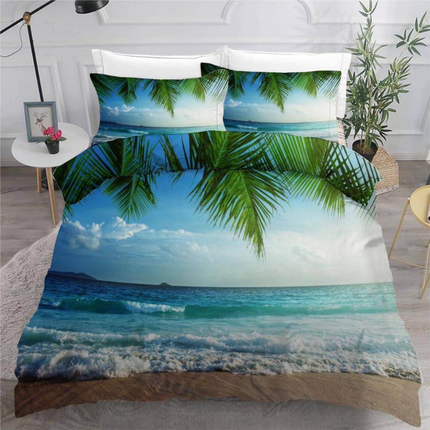 Bett mit tropischem Strand-Bettwäsche-Druck, der Palmblätter, Meereswellen und blauen Himmel in einem hellen Schlafzimmer zeigt.