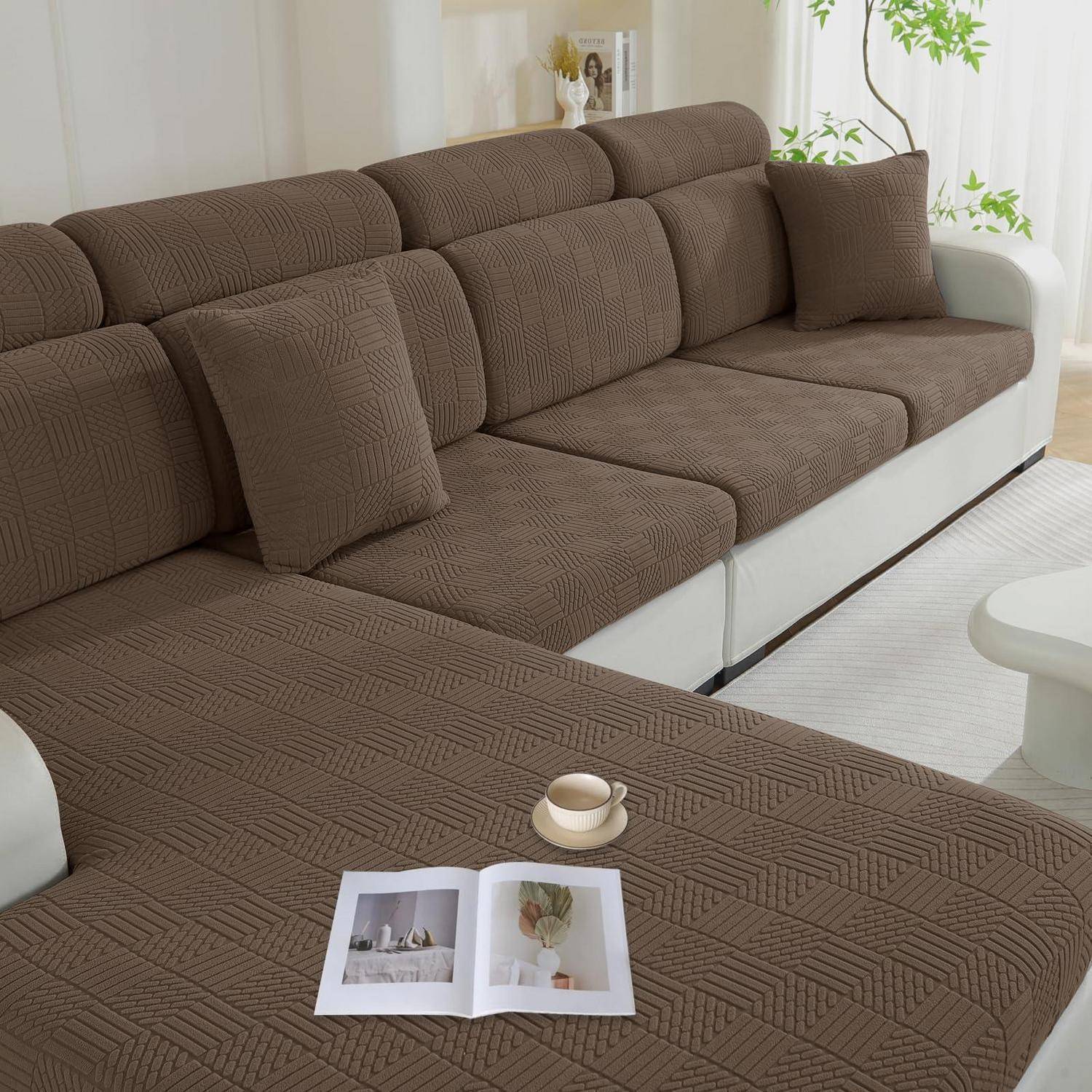 Braunes Ecksofa mit passenden Kissen in einem hellen Wohnzimmer, mit einem aufgeschlagenen Buch und einer Tasse auf der Chaiselongue.