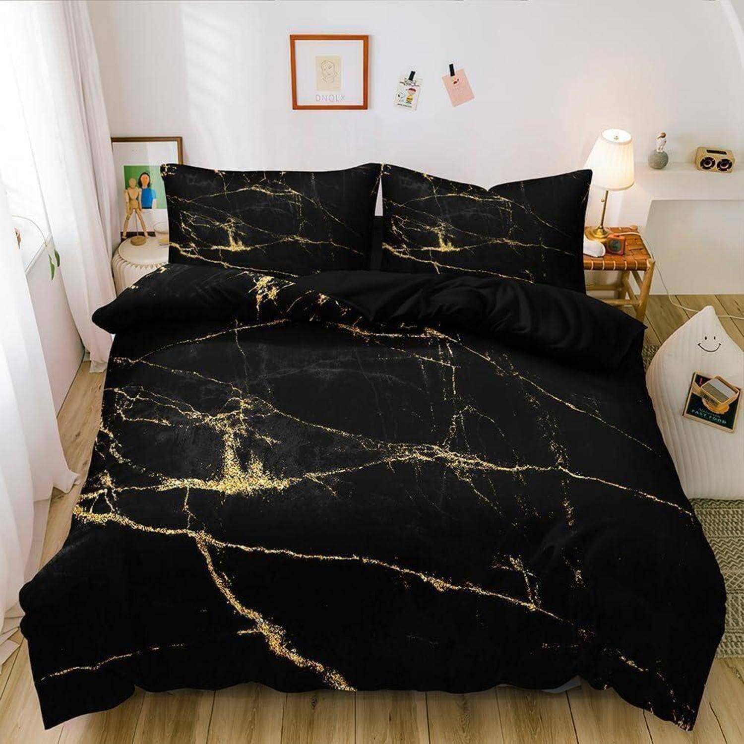 Bett mit schwarzem Marmormuster-Bettwäsche und Kissen in einem hellen, kleinen Schlafzimmer mit einer Nachttischlampe und Wandkunst.