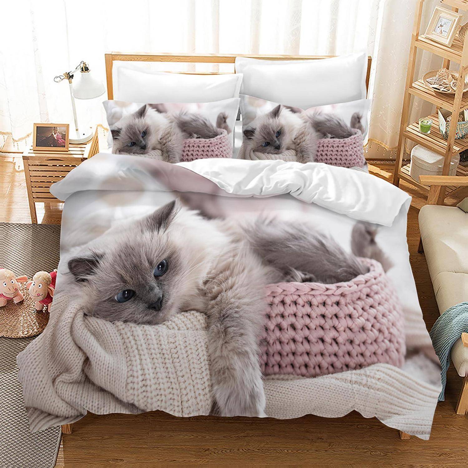 Ein Bett mit Katzendruck-Bettwäsche, auf dem ein fluffiges Kätzchen auf gestrickten Decken liegt, in einem hellen, gemütlichen Schlafzimmer.