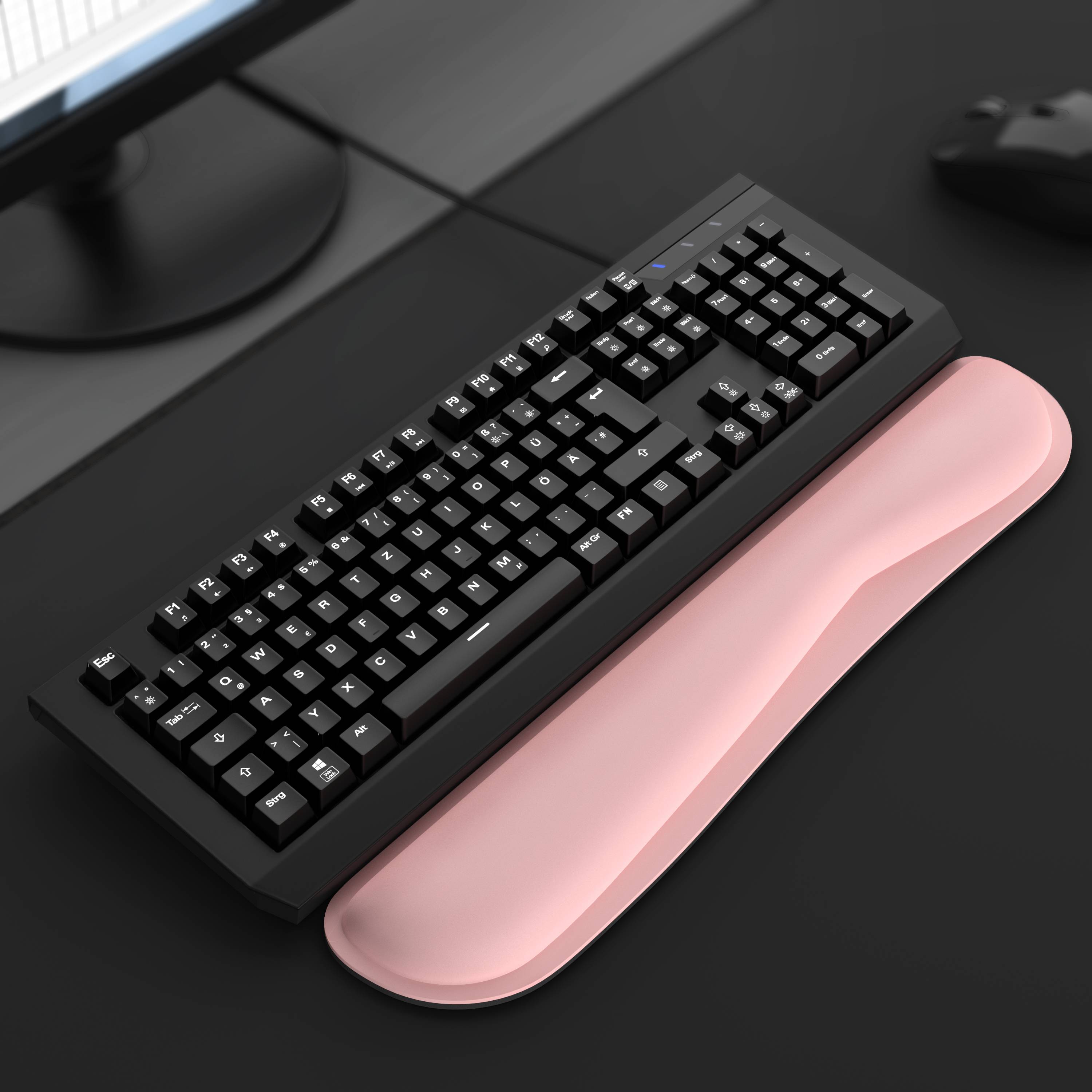 Schwarze mechanische Tastatur auf einem dunklen Schreibtisch mit einer rosa Handgelenkauflage darunter.