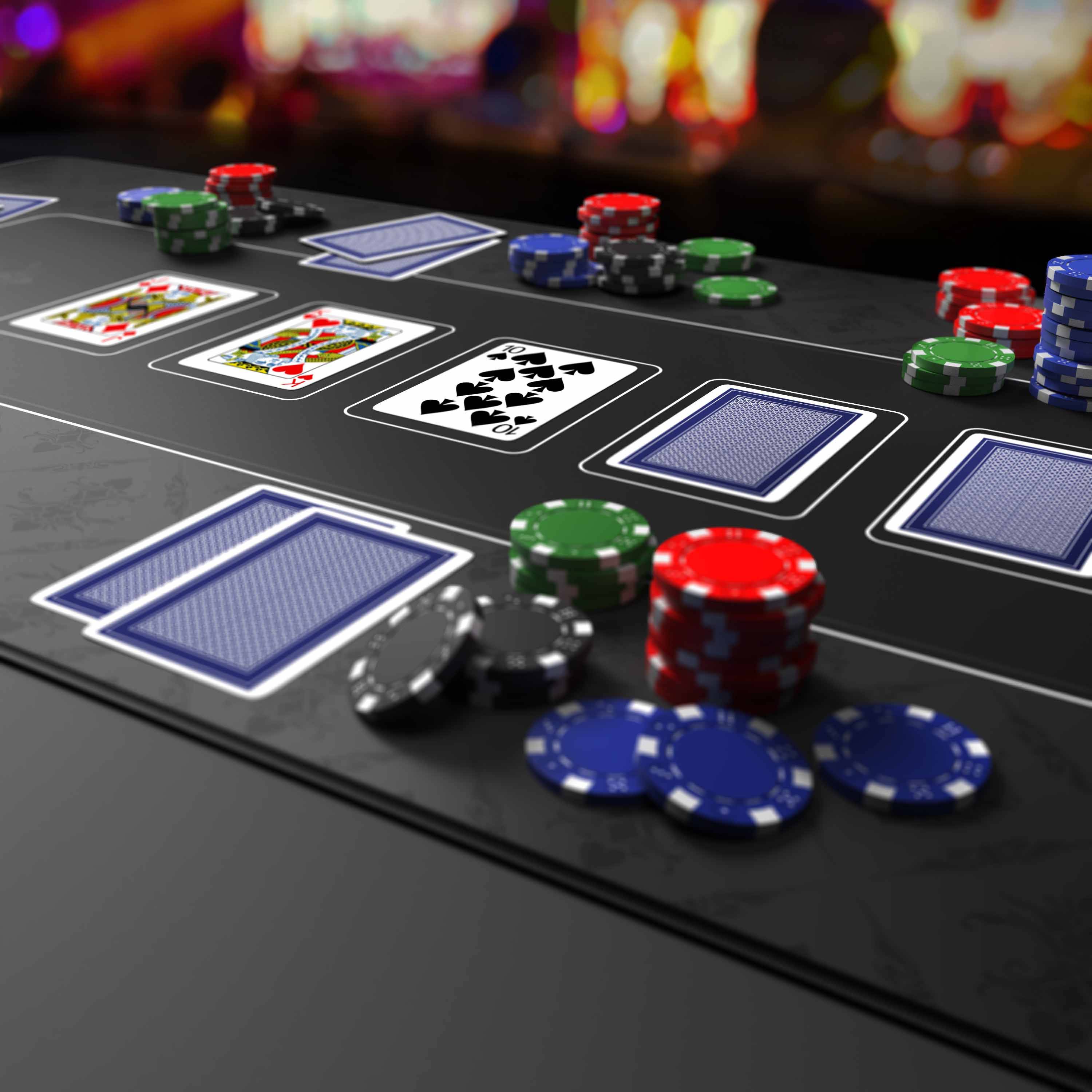 Pokertisch mit verdeckten und offenen Karten, verstreute Stapel roter, blauer, grüner und schwarzer Chips, die auf ein laufendes Kasinospiel hindeuten.