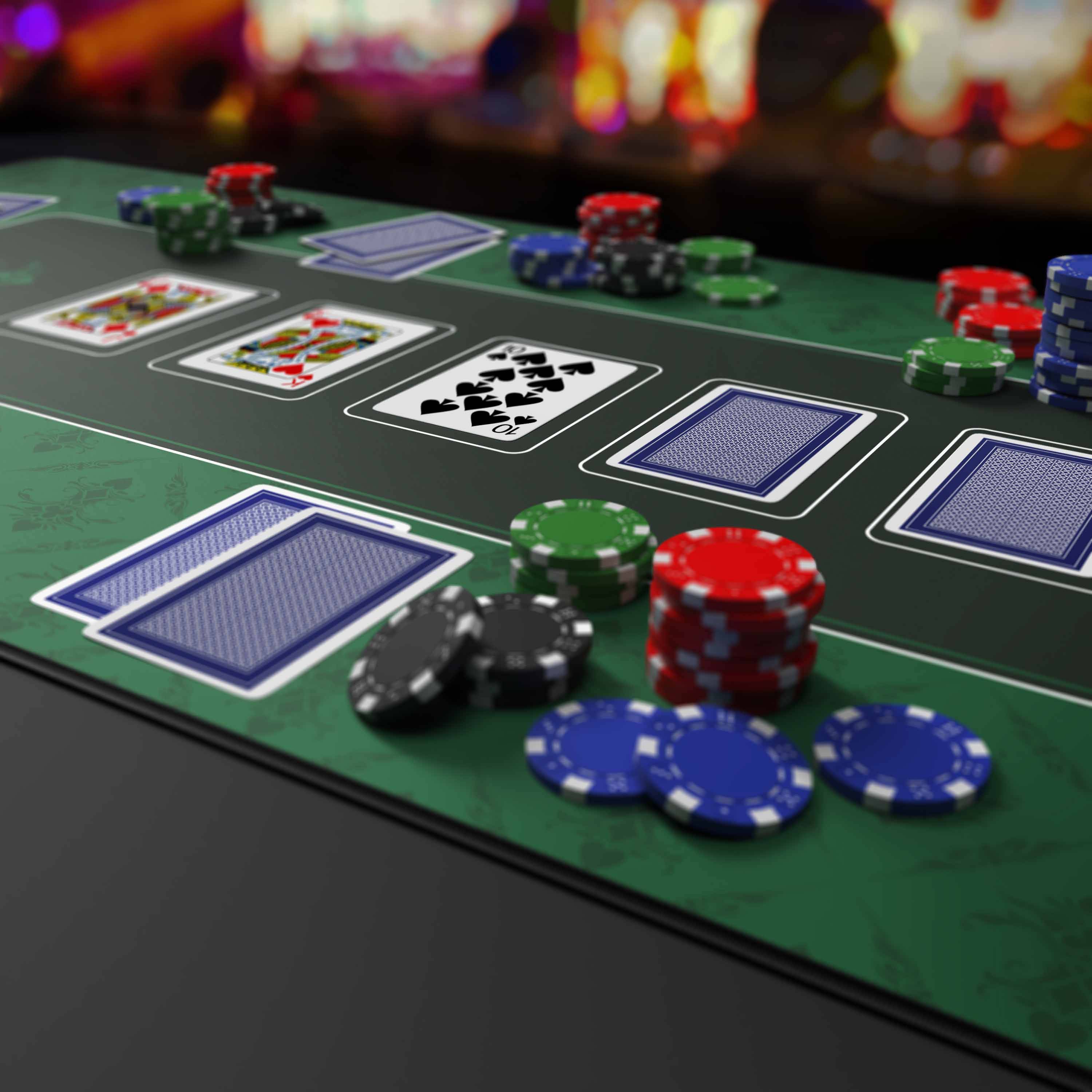 Pokertisch mit aufgedeckten und verdeckten Karten, farbenfrohen Chipstapeln und verstreuten Chips während eines Spiels