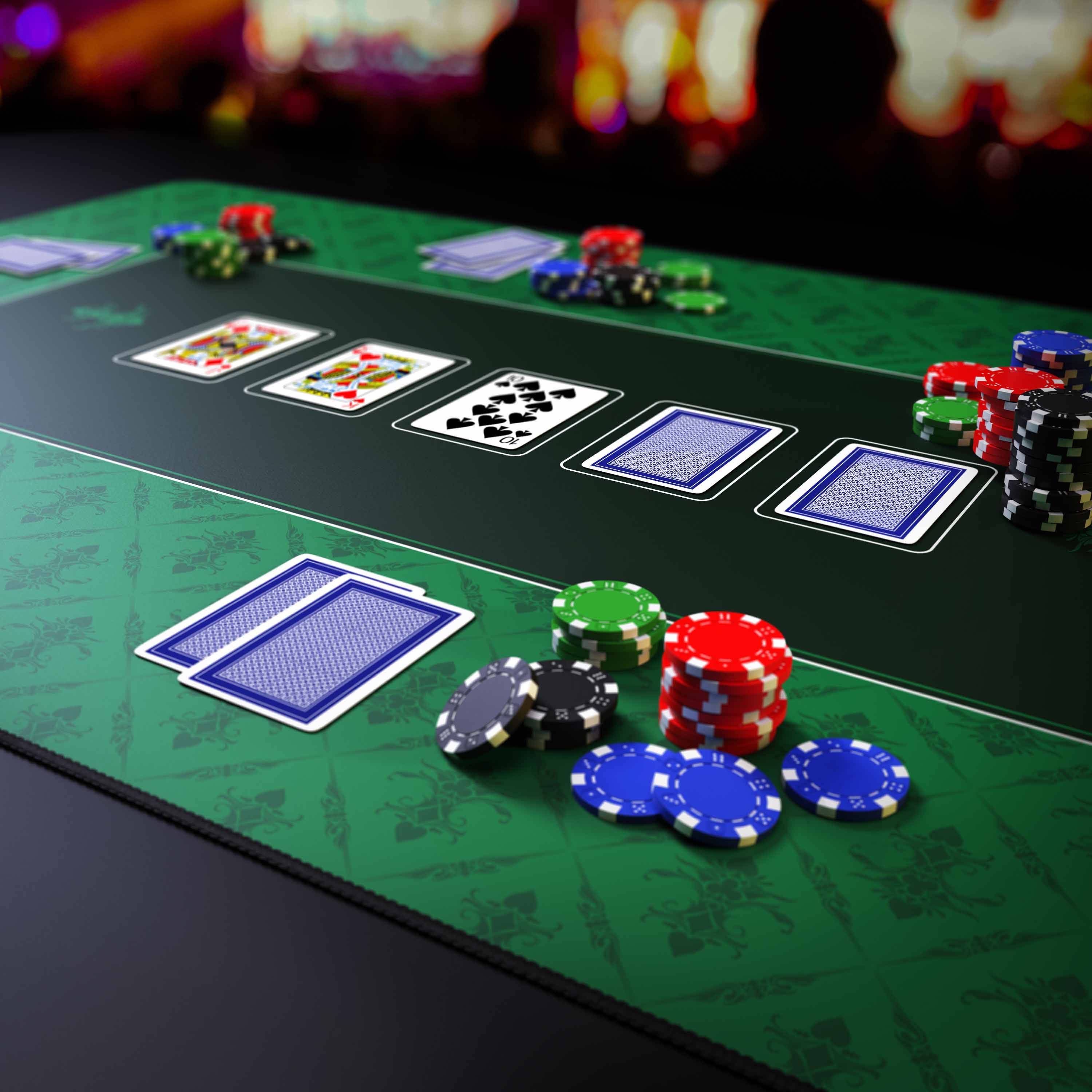 Pokertisch mit Chips und Spielkarten auf einer grünen Filzoberfläche, der ein laufendes Kartenspiel zeigt.