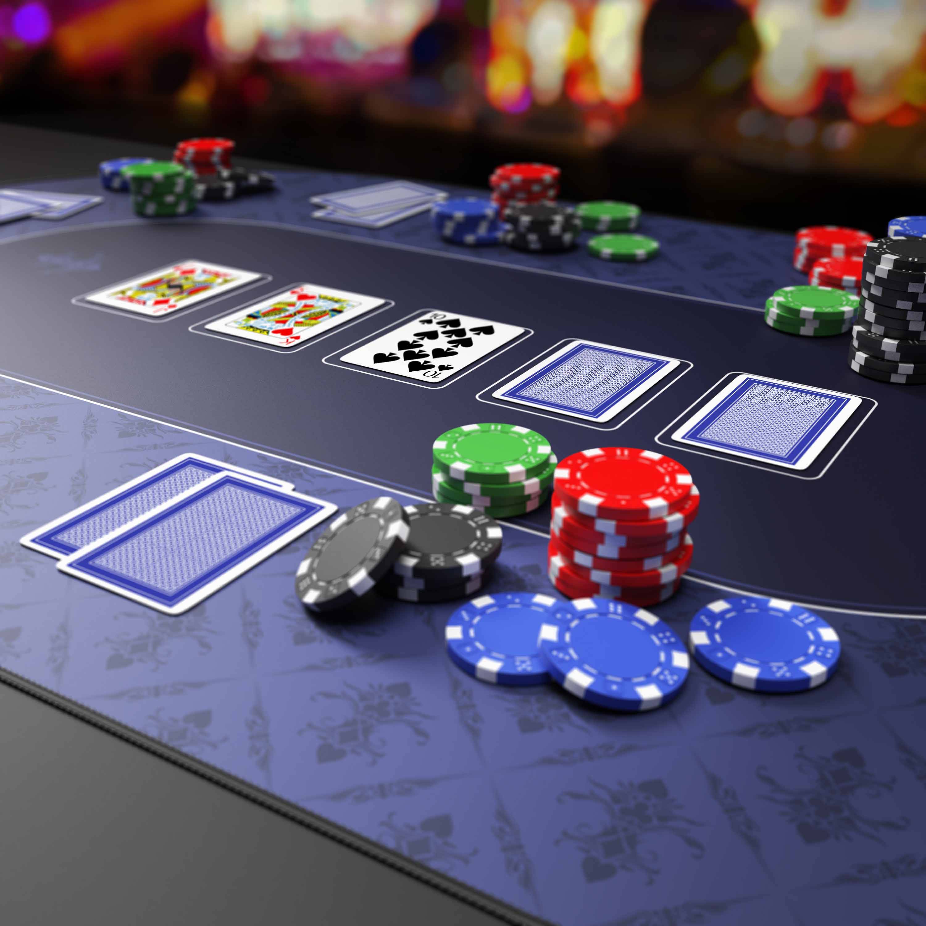 Pokertisch mit mehreren offenen und verdeckten Karten sowie Stapeln von farbigen Chips, die ein aktives Casinospiel zeigen.