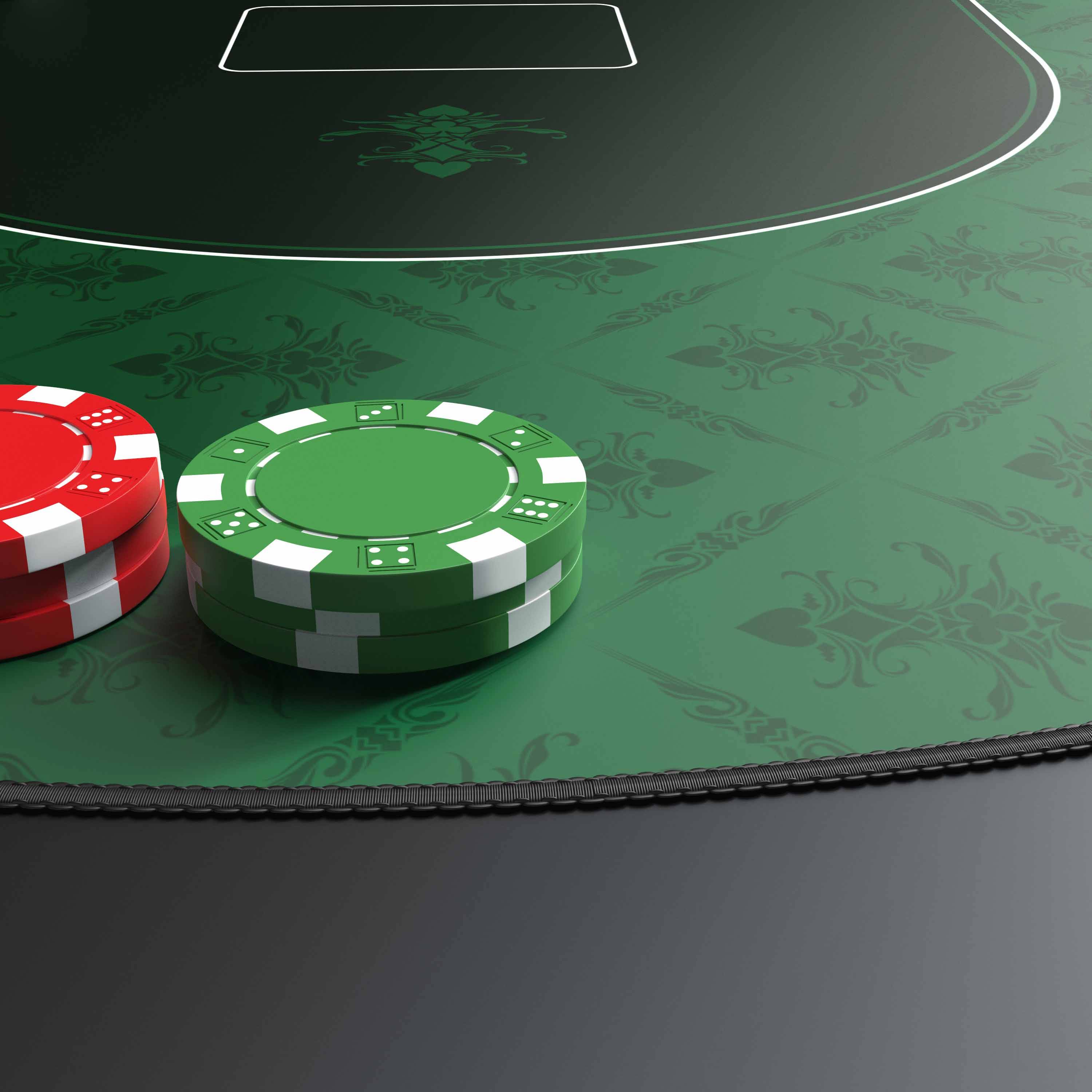 Zwei Kasinojetons, einer rot und einer grün, liegen auf einem grünen Pokertisch mit einem markierten Einsatzbereich.