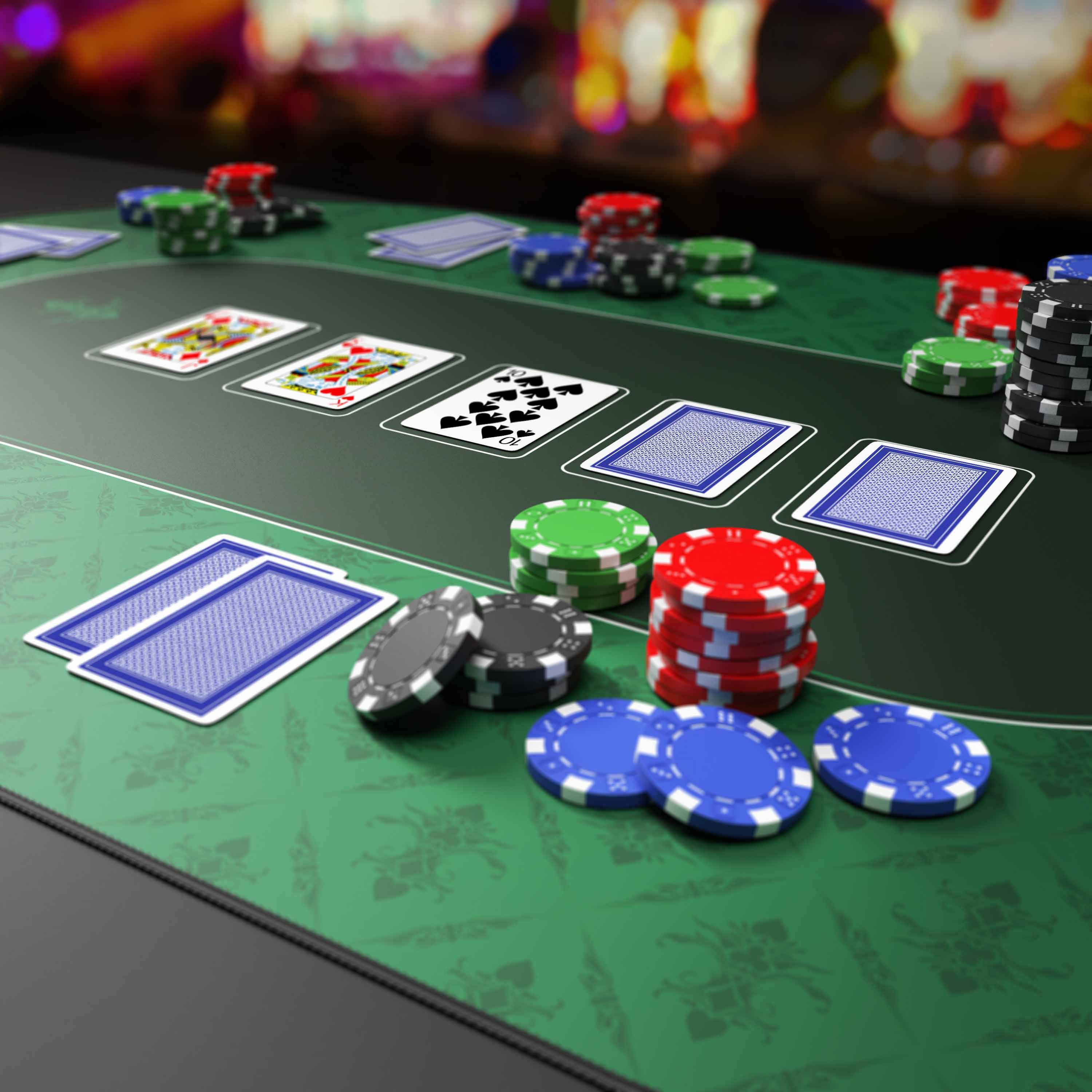 Casino-Pokertisch mit Spielkarten und Stapeln farbiger Chips auf einer grünen Filzoberfläche.