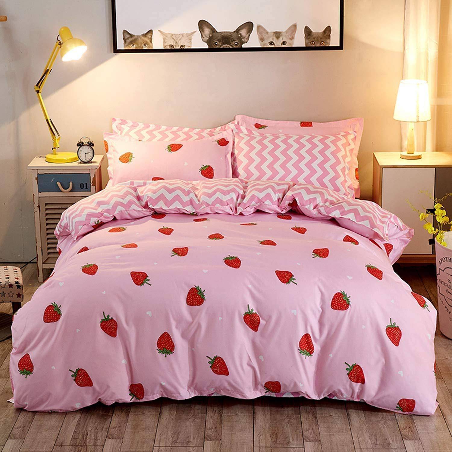 Rosa erdbeermusterige Bettwäsche auf einem ordentlich gemachten Bett in einem gemütlichen Schlafzimmer, mit Lampen und Nachttischen auf beiden Seiten.