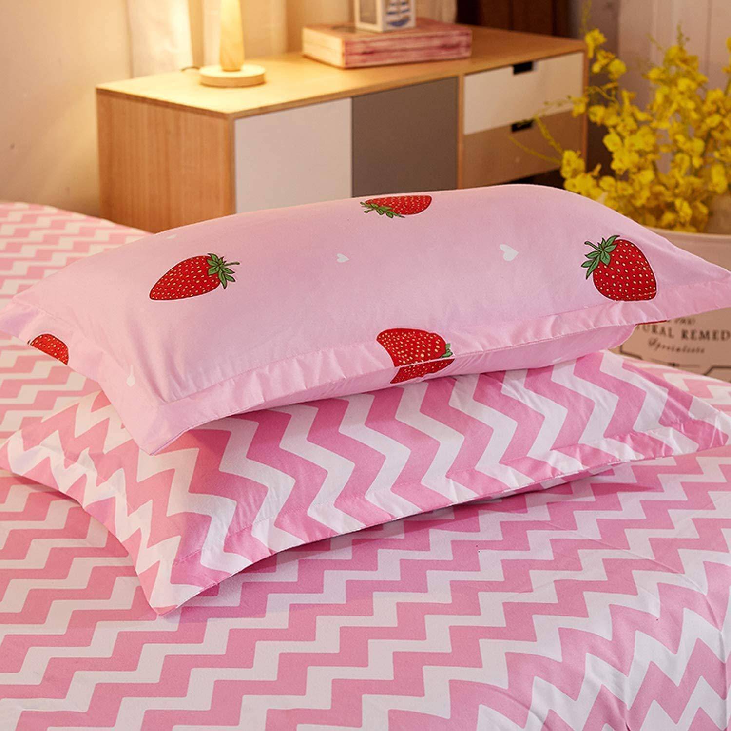 Rosa Kissen mit Erdbeermuster auf einem Bett mit rosa Chevron-Bettwäsche in einem gemütlichen Schlafzimmer.