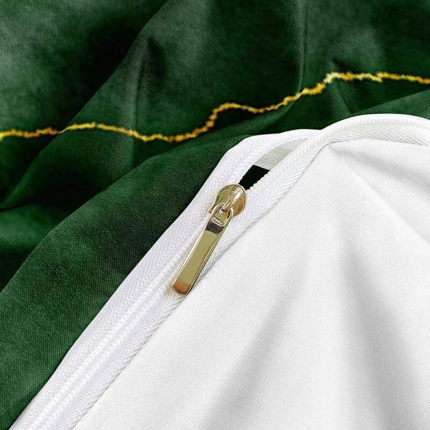 Nahaufnahme eines weißen, mit Reißverschluss versehenen Kleidungsstücks oder einer Tasche auf dunkelgrünem Stoff mit goldenem Reißverschlussschieber.