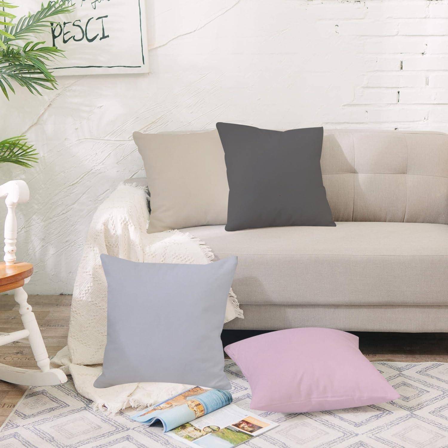 Beiges Sofa mit grauen und beigen Kissen, ein lavendelfarbenes Kissen auf dem Boden und eine Zeitschrift neben einem Schaukelstuhl in einem hellen Wohnzimmer.