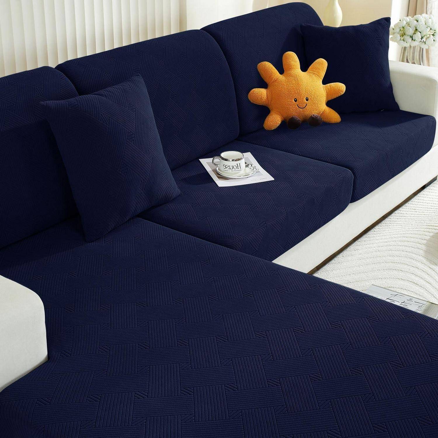 Dunkelblau gepattertes Sofa in einem hellen Wohnzimmer, mit einem orangefarbenen sonnenförmigen Kissen und einer Tasse auf einem Tablett.