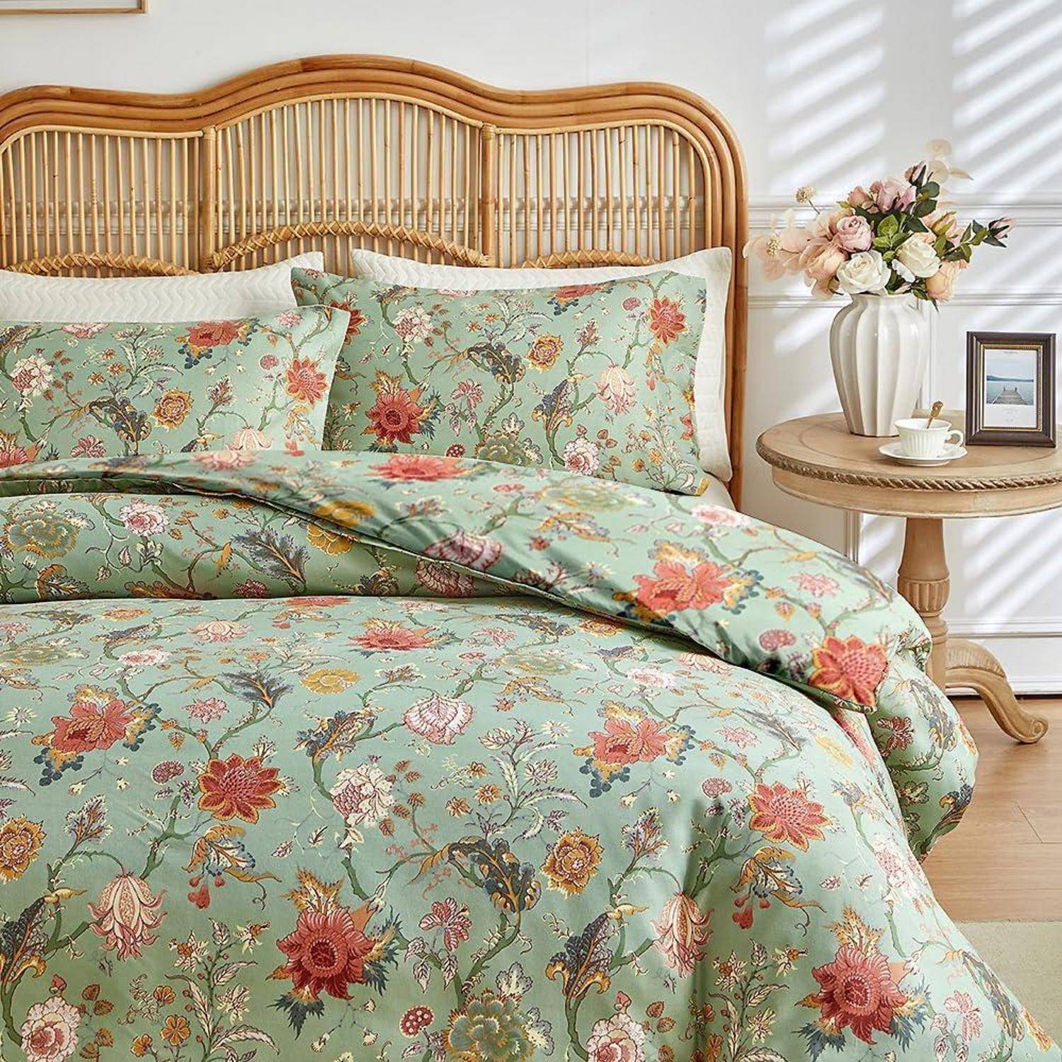 Floral mint-grünes Bettwäscheset auf einem Bett mit Korbgeflecht-Kopfteil, mit einem Nachttisch, auf dem Blumen, eine Tasse und ein Rahmenfoto stehen.