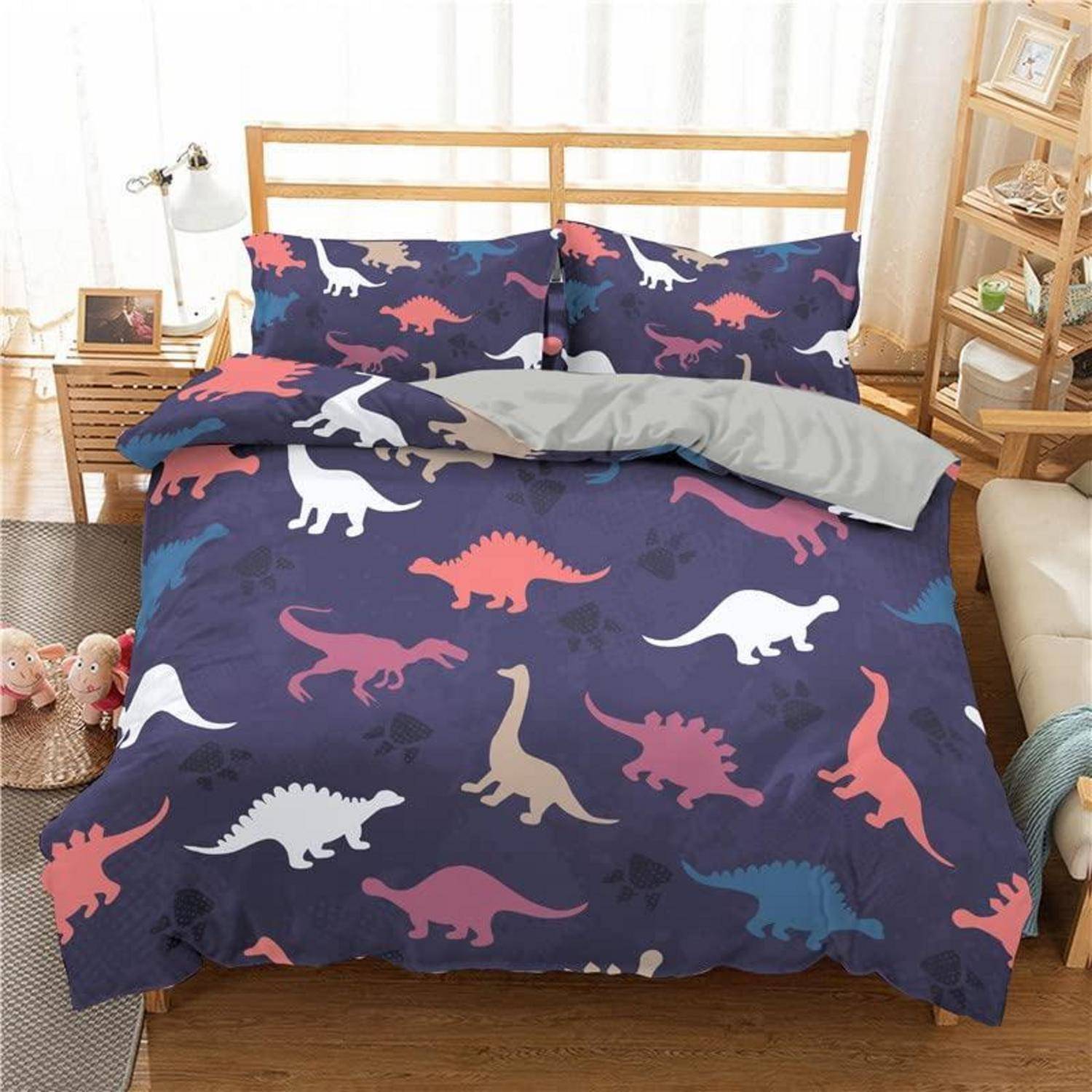 Ordentlich gemachtes Bett mit dunklem Dinosaurier-Muster-Bettwäsche, passenden Kissen und einer grauen Decke in einem hellen Schlafzimmer.