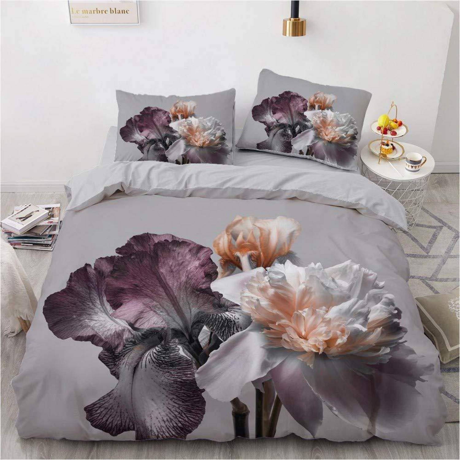 Bett mit grauer Blumenbettwäsche mit großen lila und pfirsichfarbenen Blumen auf der Bettdecke und Kissenbezügen in einem minimalistischen Schlafzimmer.