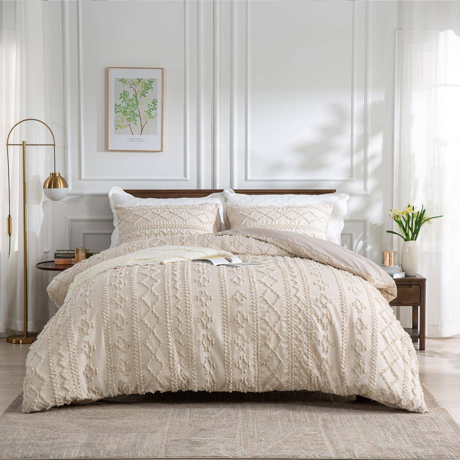 Ein ordentlich gemachtes Bett mit cremefarbener strukturierter Bettwäsche und Kissen in einem hellen, minimalistischen Schlafzimmer mit gerahmter Wandkunst, Lampen und Blumen.