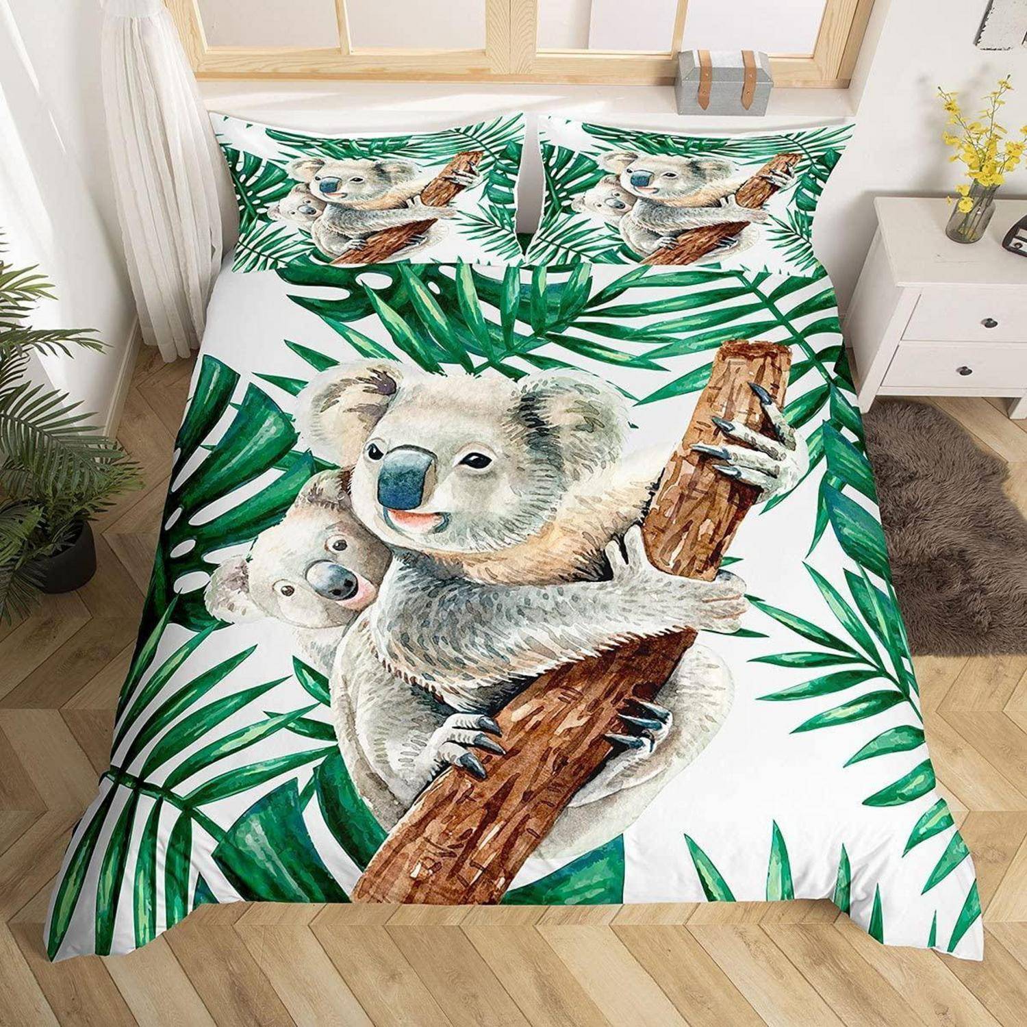 Koala-bedset mit Aquarell-Koalas und grünen tropischen Blättern auf einem Bett in einem hellen Schlafzimmer.