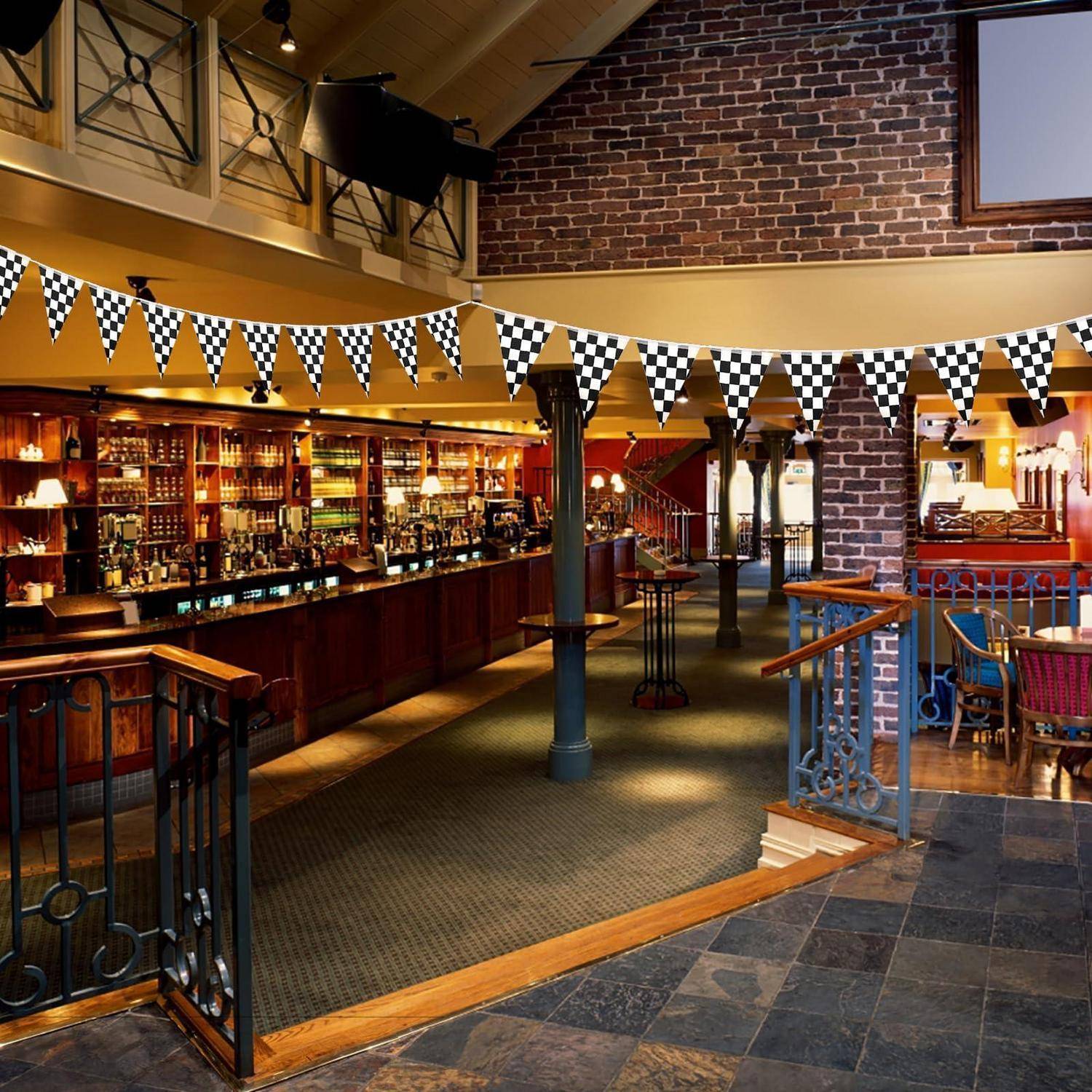 Leeres Pub-Interieur mit Theke, Hockern, karierter Girlande, Ziegelmauern und Esstischen unter warmer Beleuchtung.
