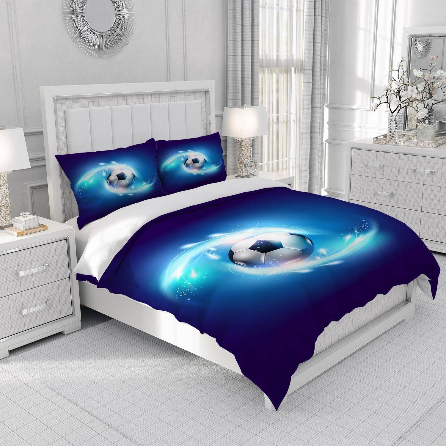 Schlafzimmer mit einem Bett, das mit einer blauen Fußball-Bettwäsche und passenden Kissen bezogen ist, zentriert in einem hellen weißen Raum mit Nachttischen und einer Kommode.
