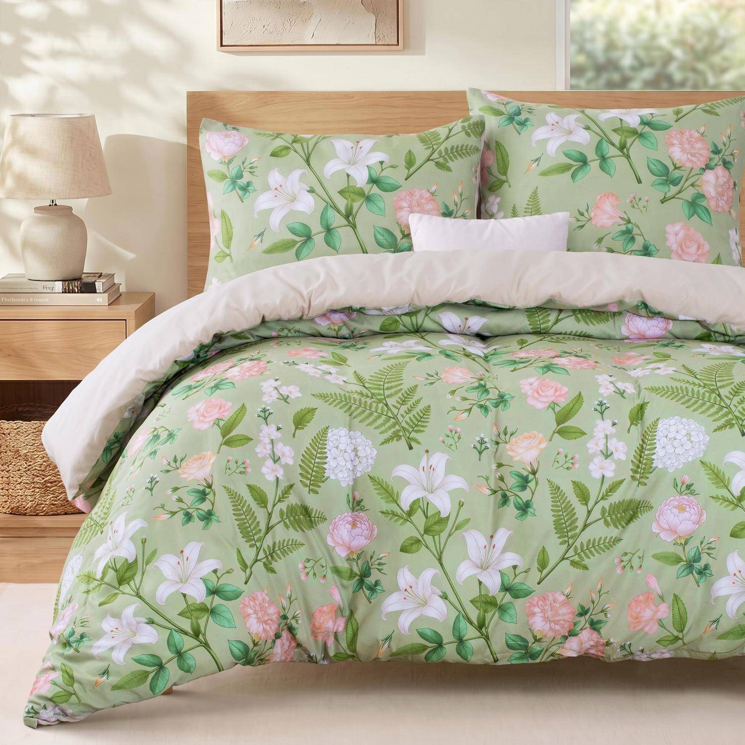 Grünes Blumenbettset mit rosa und weißen Blüten auf einem gemachten Bett in einem hellen Schlafzimmer.