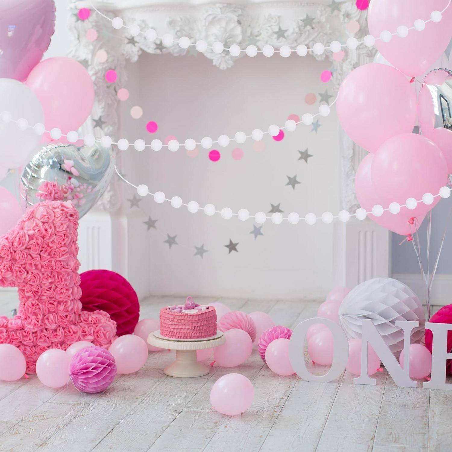 Rosa Erste-Geburtstags-Party-Setup mit Luftballons, Girlanden, Sterndekoration, einem Kuchen auf einem Ständer und großen 