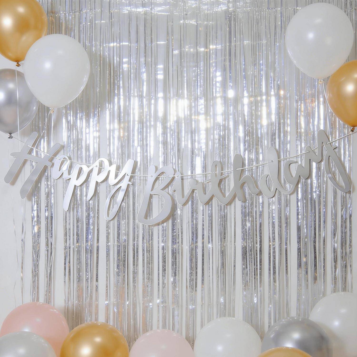 Silbernes „Alles Gute zum Geburtstag"-Banner mit weißen, goldenen und rosa Ballons vor einem glänzenden metallischen Partyhintergrund.