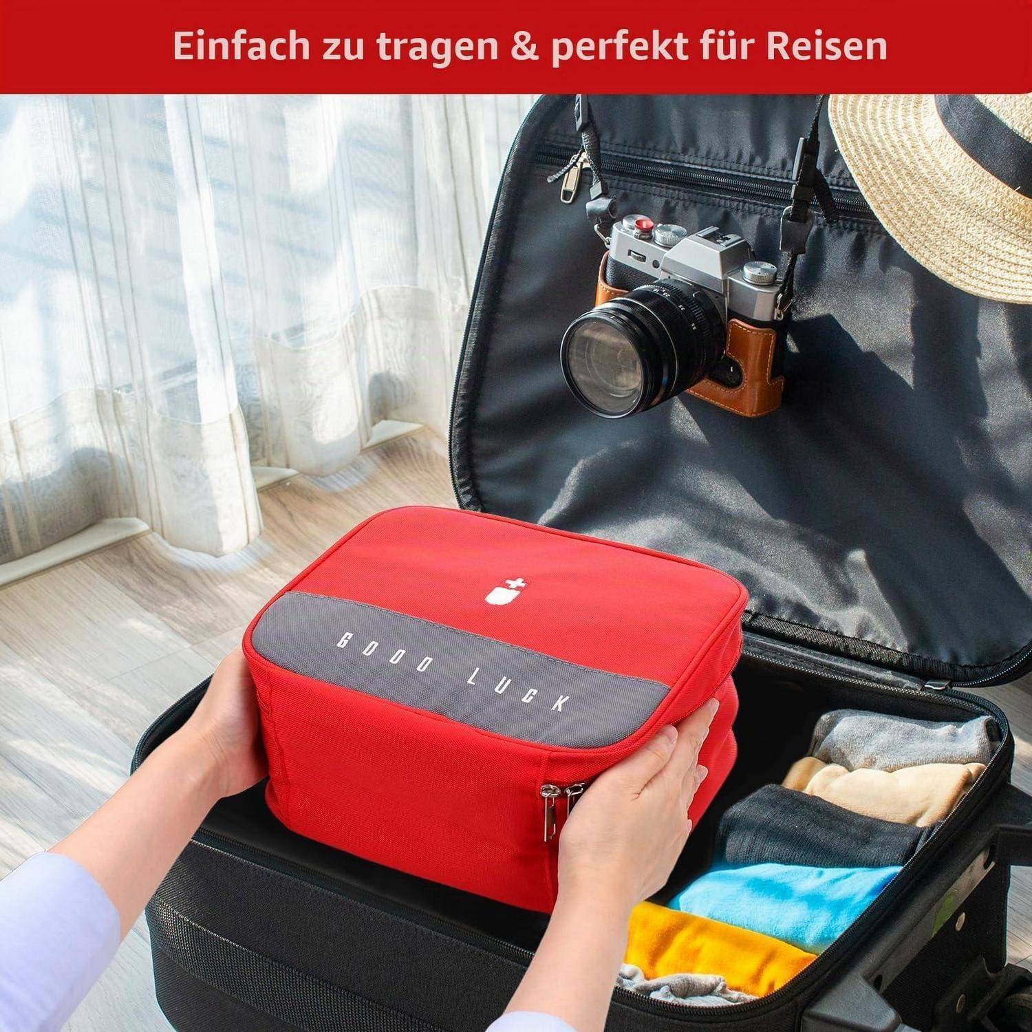 Roter Reise-Organizer-Packwürfel wird in einen offenen Koffer mit einer Kamera im Deckel gelegt und fördert einfaches Reiseverpacken.