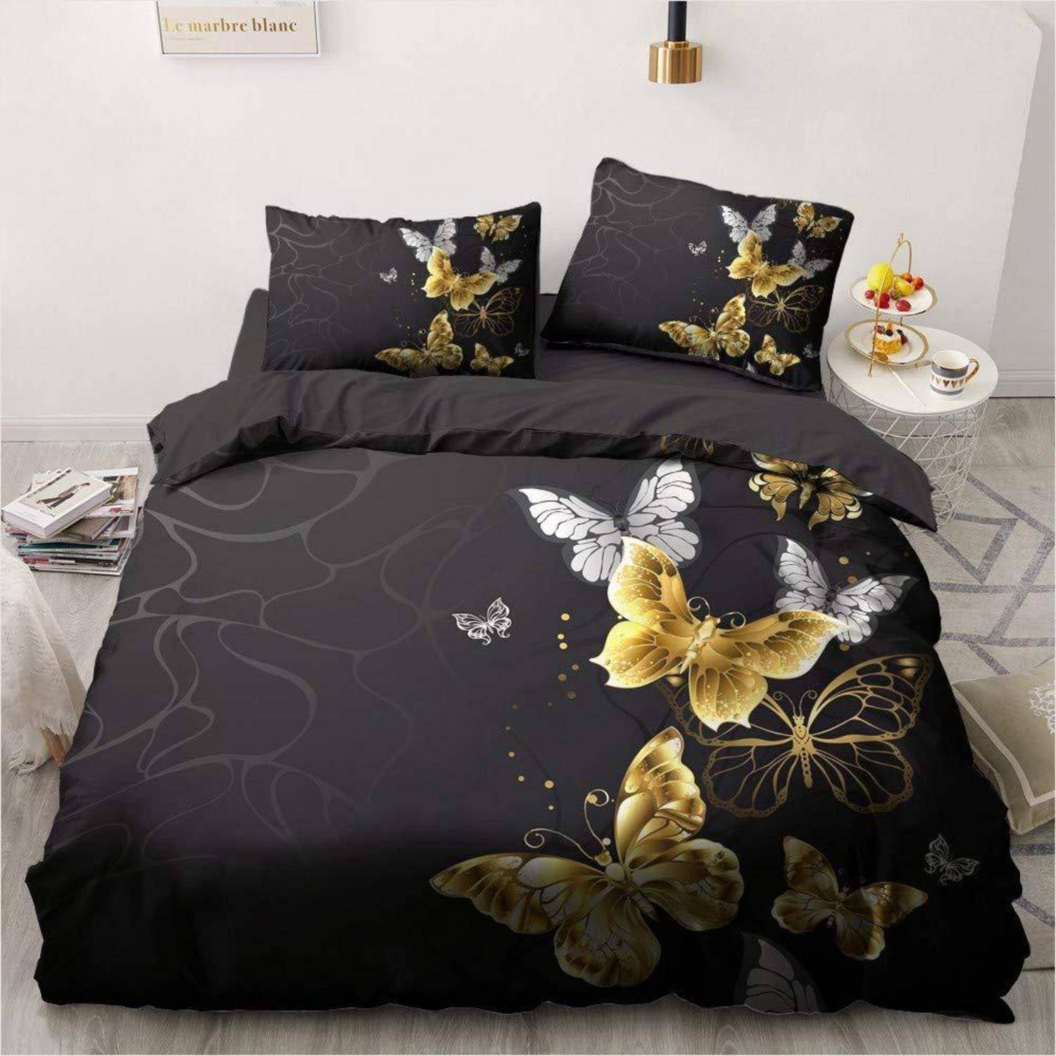 Schwarzes Bettwäscheset mit goldenem und weißem Schmetterlingsmuster auf einem gemachten Bett, einschließlich zwei passender Kissenbezüge und Bettdeckenbezug.