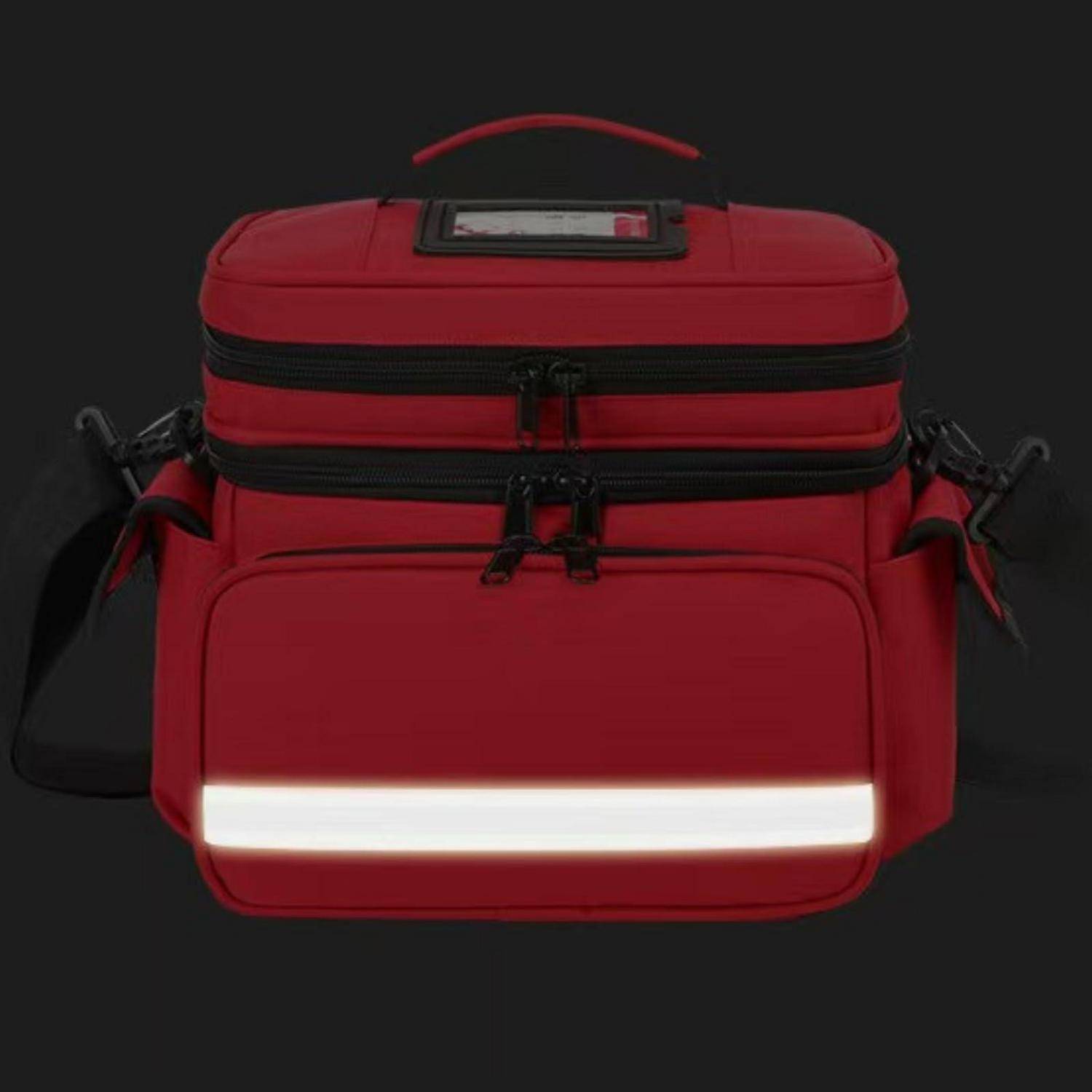 Rote Reisetasche mit Schultergurt, Griff und reflektierendem Vorderstreifen auf dunklem Hintergrund.