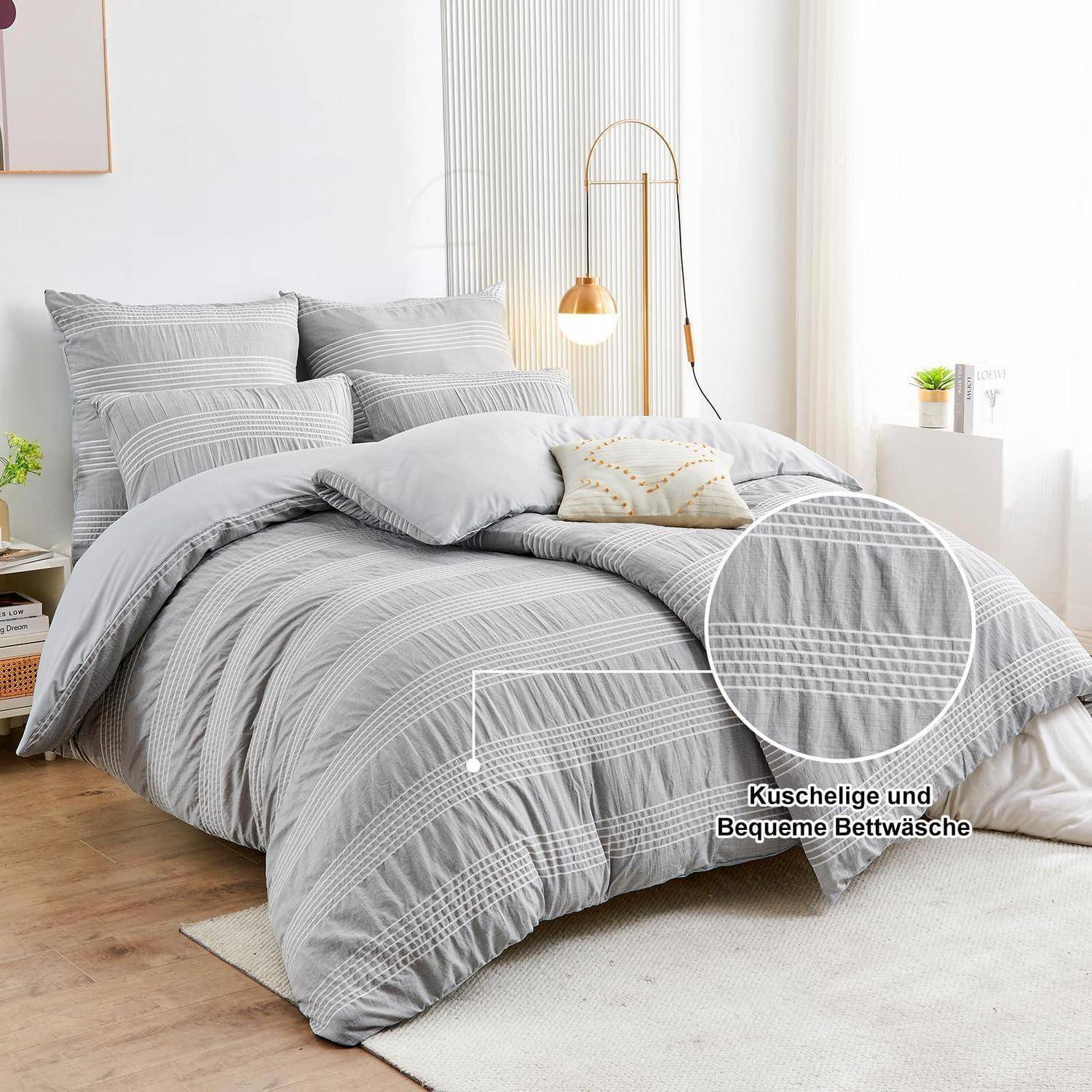 Grau gestreiftes Bettwäscheset auf einem gemachten Bett in einem hellen Schlafzimmer, mit einer vergrößerten Nahaufnahme, die die Textur der Bettdecke hervorhebt; der Text lautet „Kuschelige und Bequeme Bettwäsche"