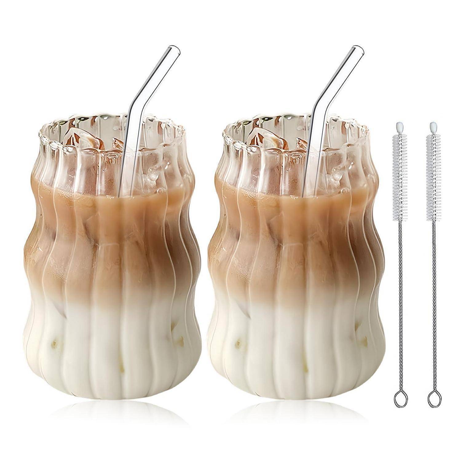 Zwei geschichtete Eiskaffee-Getränke in gewellten Glastassen mit Metallstrohhalmen, dargestellt neben zwei Reinigungsbürsten.
