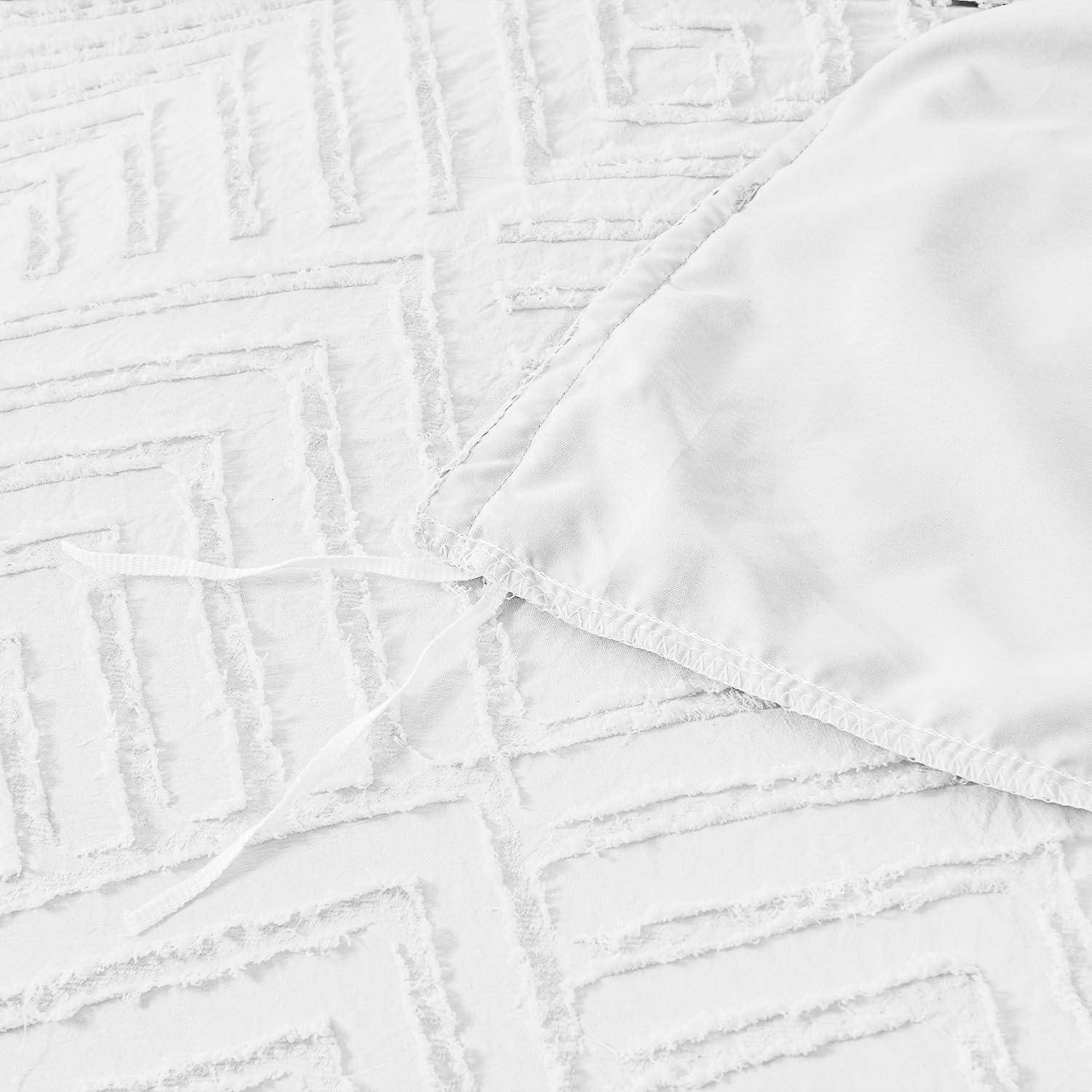 Nahaufnahme einer weißen strukturierten Tagesdecke mit einer glatten weißen Kissenkante, die sich darüber überlappt.
