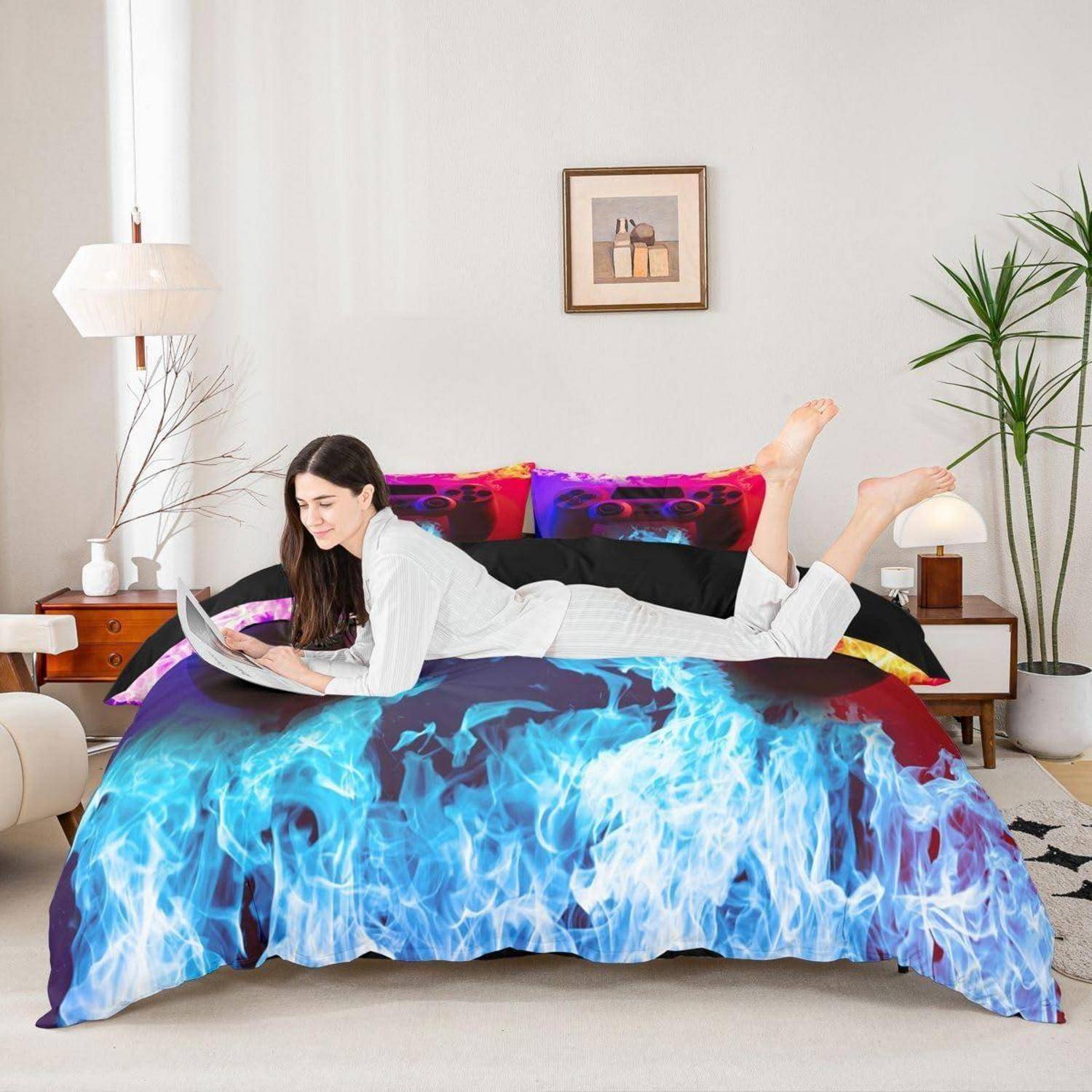 Frau, die auf einem Bett liegt und einen Laptop benutzt, mit blauer Bettwäsche mit Flammenmuster in einem hellen Schlafzimmer.