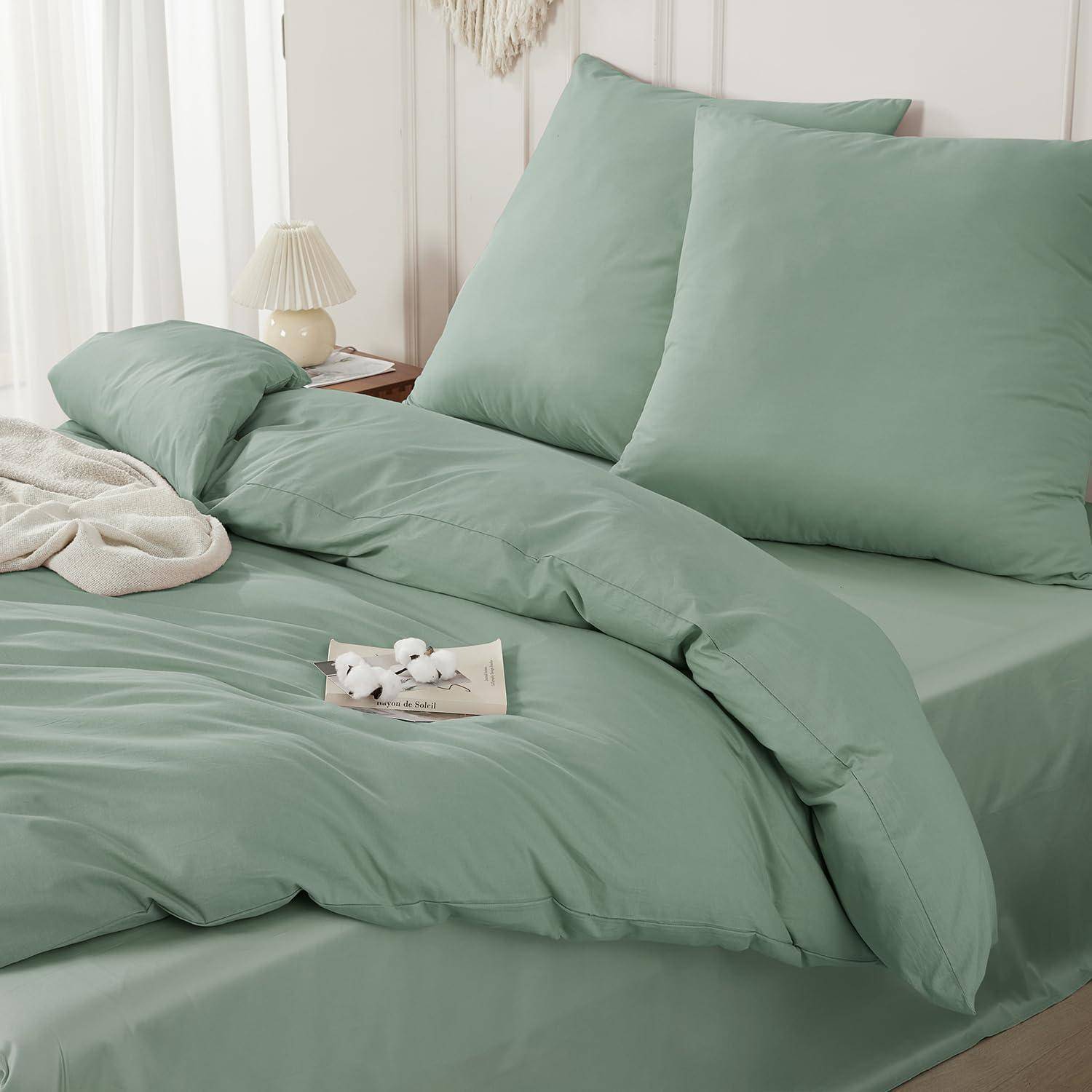 Minzgrüne Bettwäscheset auf einem ordentlich gemachten Bett mit Kissen, Bettdecke und Laken in einem hellen Schlafzimmer.