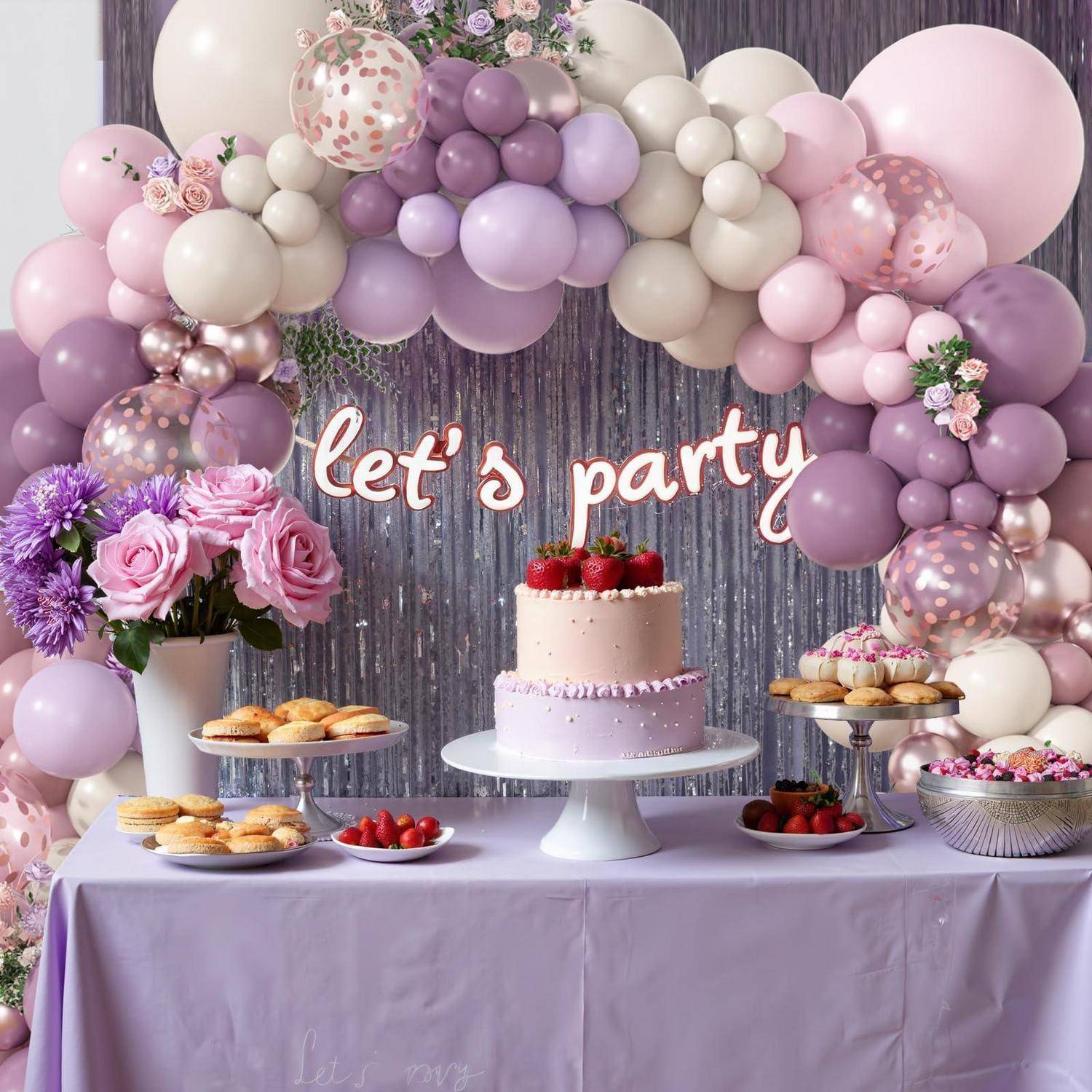 Pastell-Luftballon-Girlande über einem Dessert-Tisch mit einer zweistöckigen Torte, Blumen, Gebäck und einem „Let's Party
