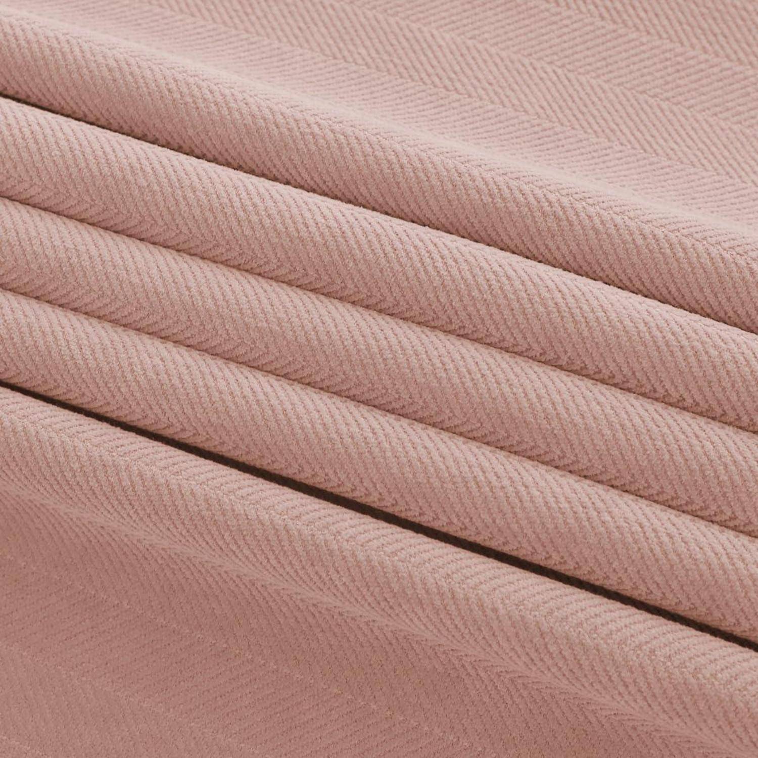 Nahaufnahme von gefaltetem staubigem rosa geripptem Stoff mit diagonalen Falten und weicher Textur.