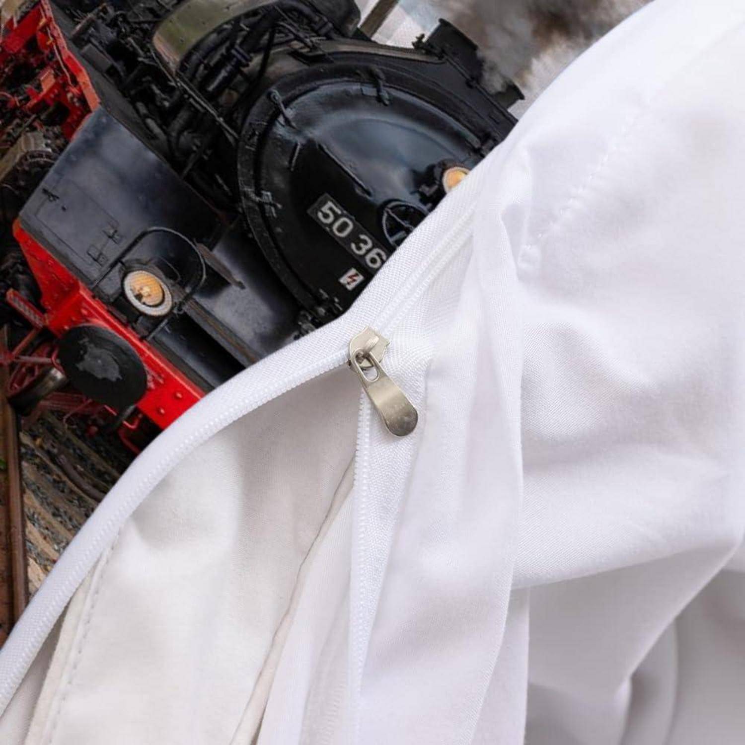 Nahaufnahme einer weißen Stoff-Tasche oder -Abdeckung mit Reißverschluss und metallischem Reißverschlussschieber, die teilweise eine rot-schwarze Lokomotive dahinter verdeckt.