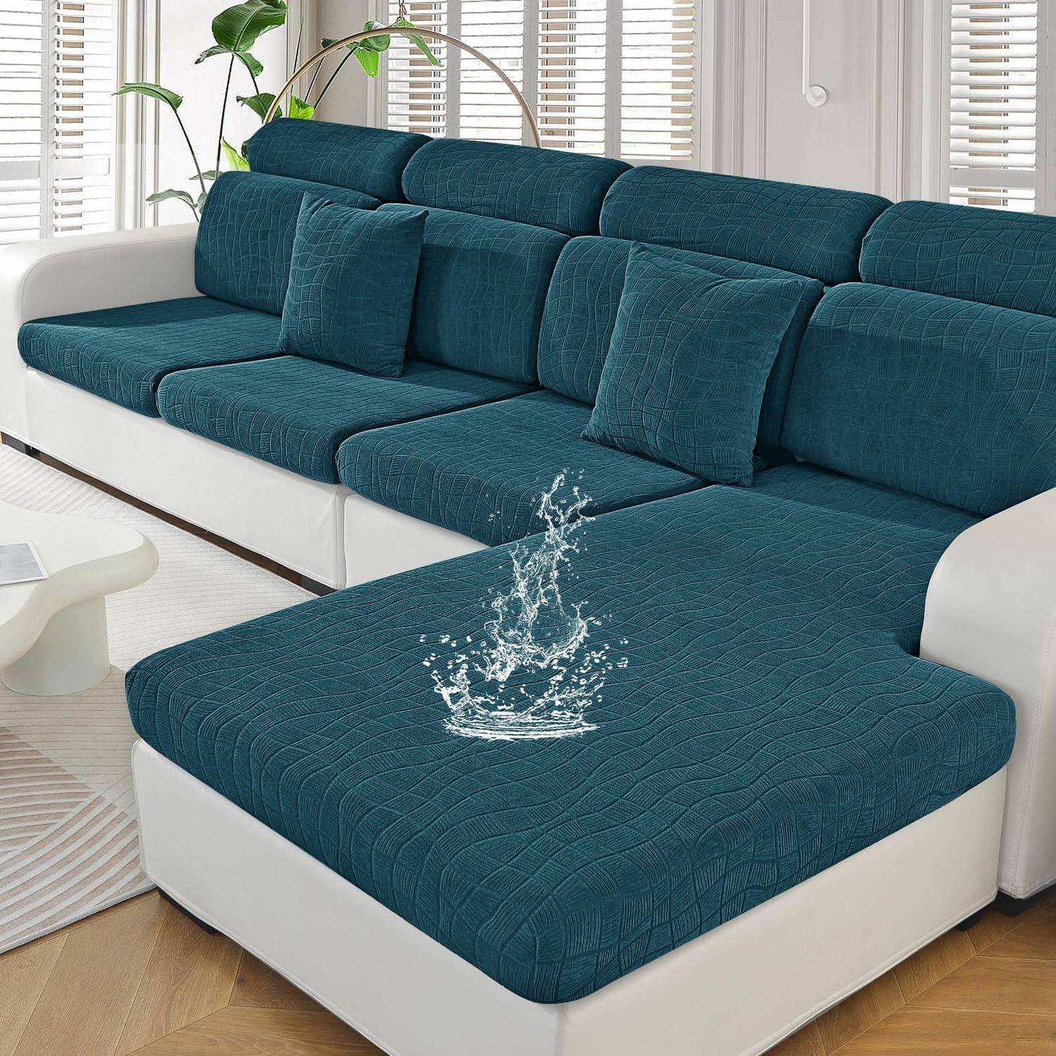 Teal-farbiges Ecksofa mit weißer Basis und einem Wassertropfen auf dem Sitzkissen, der die wasserabweisende Stoffbeschaffenheit zeigt, in einem hell erleuchteten Wohnzimmer.