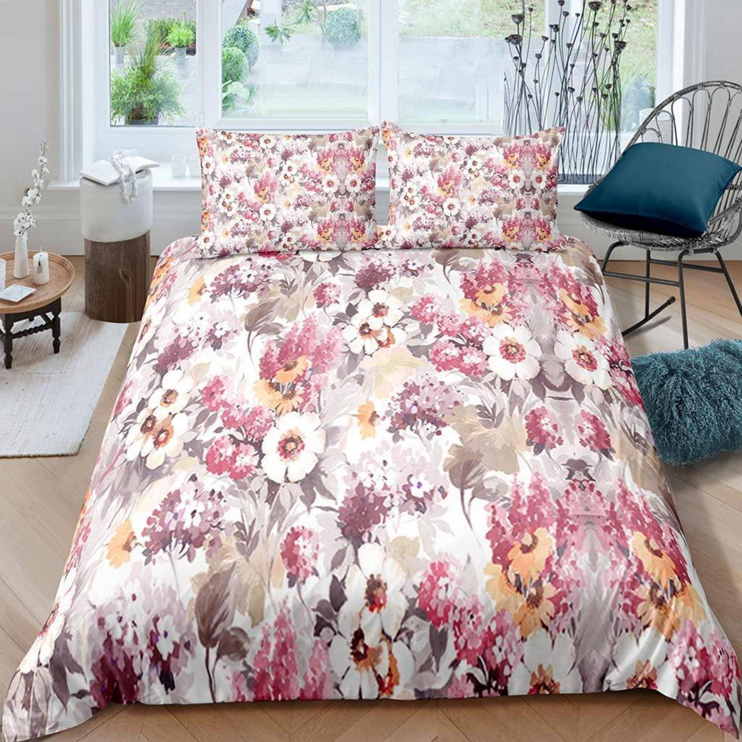 Blumenmuster-Bettdecke und Kissenbezüge in einem hellen Schlafzimmer mit rosa, weißen und beigen Blüten.