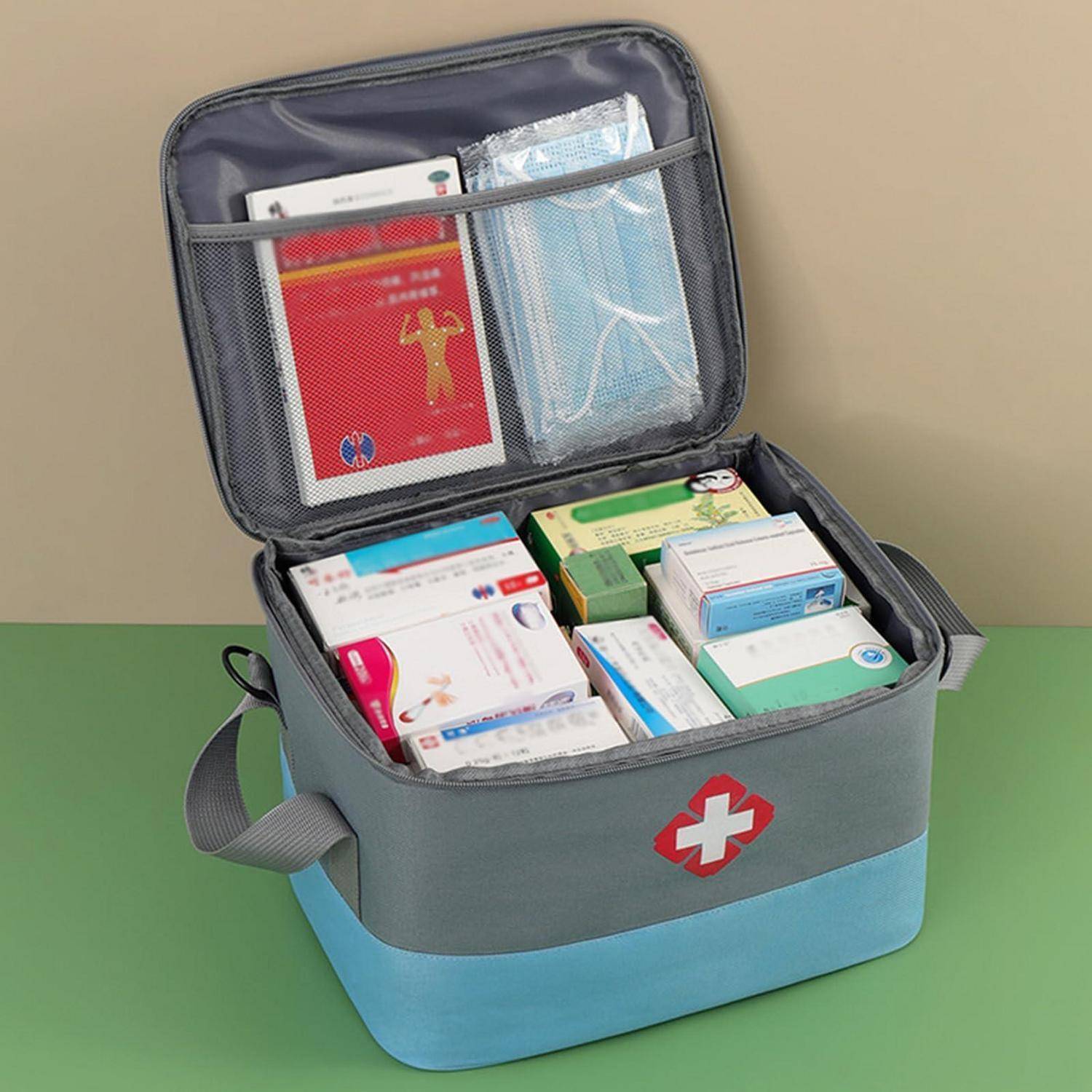 Offenes Erste-Hilfe-Set mit gemischten medizinischen Hilfsmitteln und Boxen, einschließlich Masken und verpackter Artikel, auf einer grünen Oberfläche.