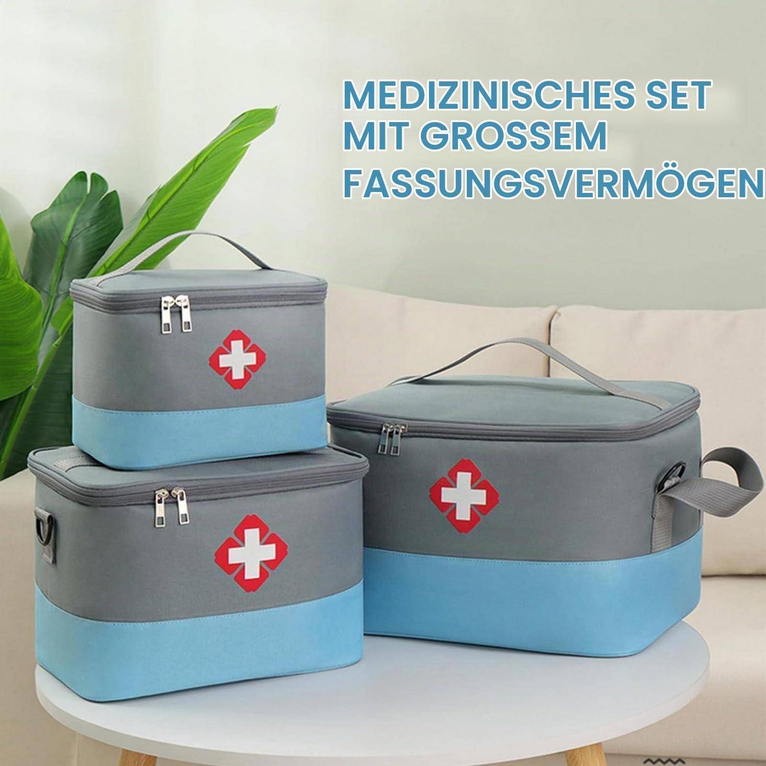 Drei grau-blaue medizinische Aufbewahrungstaschen mit roten Kreuzsymbolen auf einem Tisch, beschriftet in deutscher Sprache „Medizinisches Set mit großem Fassungsvermögen".